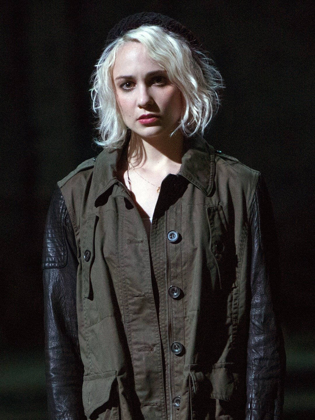 Sense8 桌布 壁紙 — 一位擁有鉑金色頭髮和黑色貝雷帽的女性，在昏暗的場景中穿著棕色背心搭配皮革袖子，專注地凝視著。