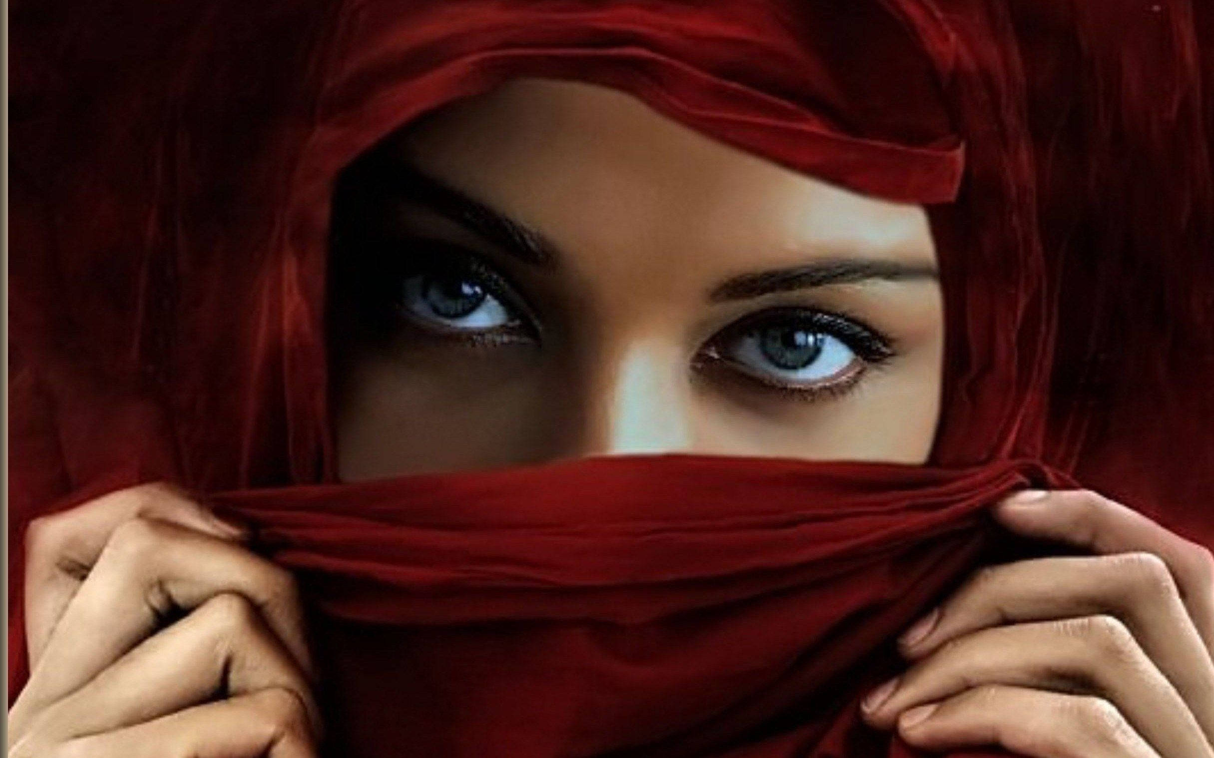 muslim 桌布 壁紙 — 一位擁有銳利藍色眼睛的女性透過雙手握著的濃郁紅色面紗窺視。