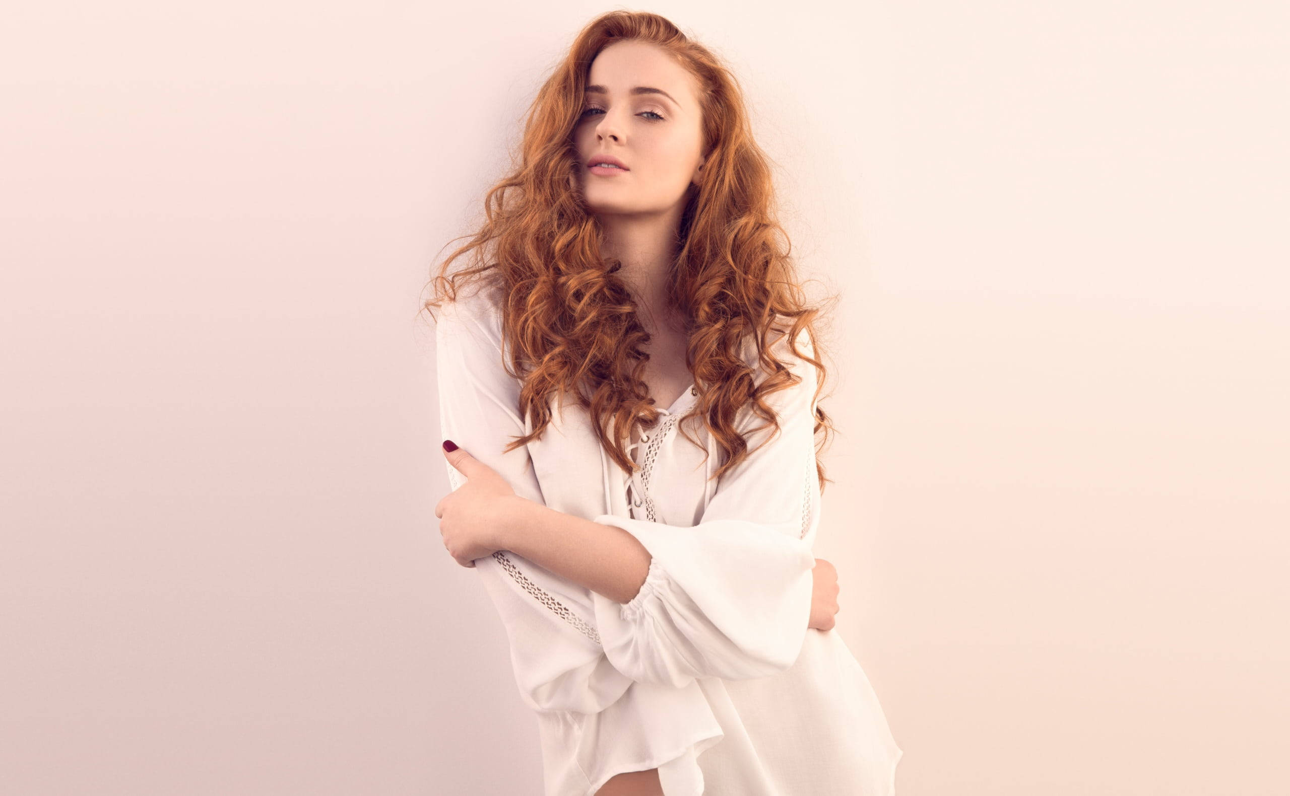 Sophie 桌布 壁紙 — 一位擁有長捲紅髮的女性，在柔和的粉紅色背景前穿著白色襯衫。