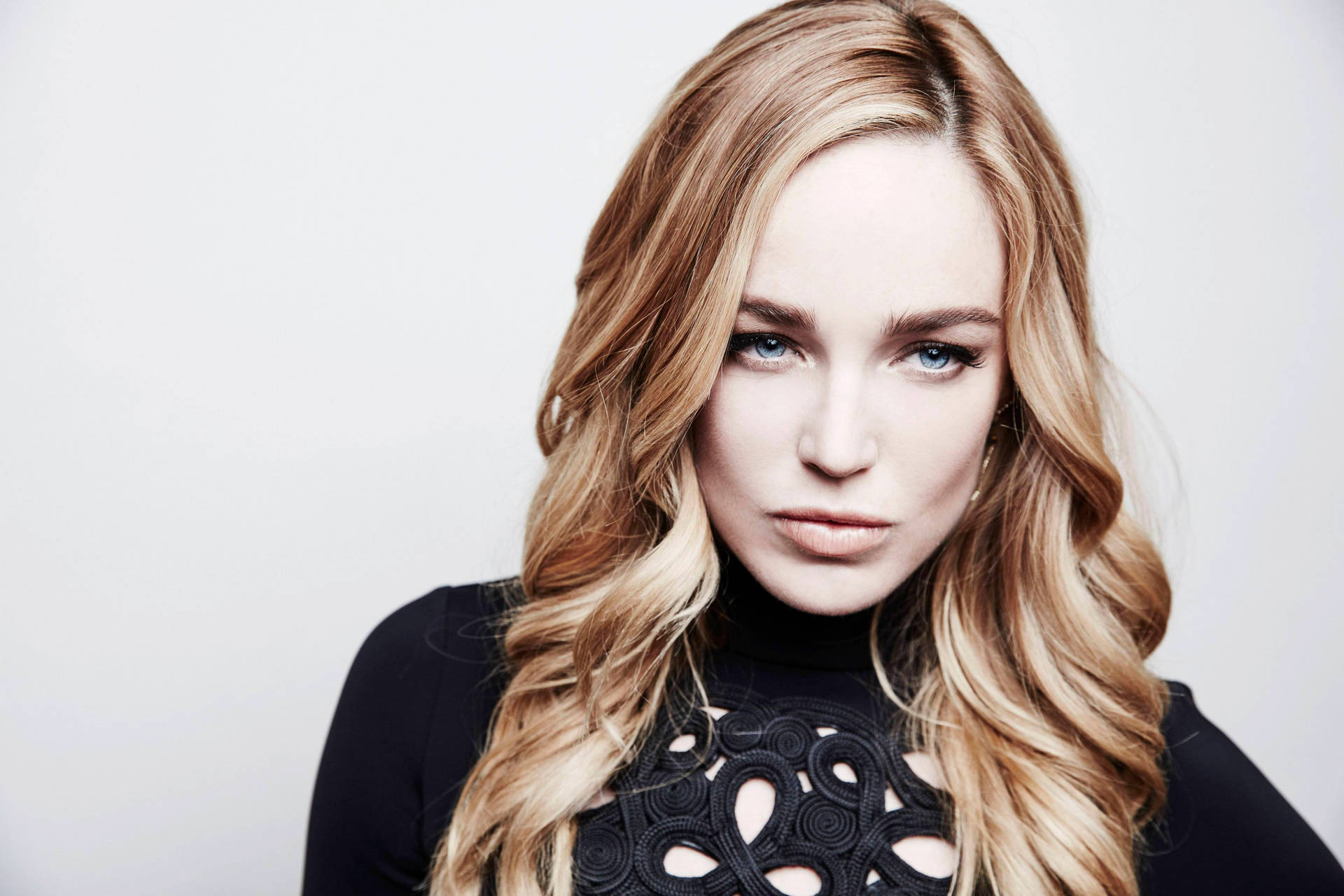 一位金髮藍眼的女性，在工作室肖像中穿著黑色蕾絲上衣。 — Caity Lotz 動圖 壁紙