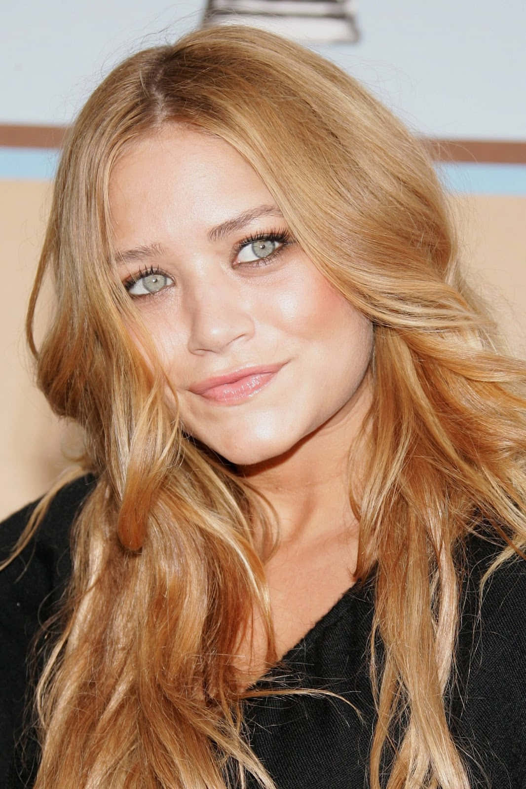 Mary Kate Olsen 桌布 壁紙 — 一位擁有長波浪金髮和綠色眼睛的女性近距離肖像，對著鏡頭溫柔微笑。