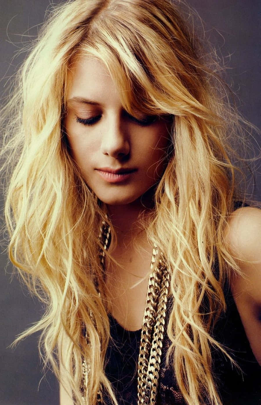 Mélanie Laurent 桌布 壁紙 — 一位擁有長波浪金髮和閉著眼睛的女性，在深色背景前佩戴多層金鏈。