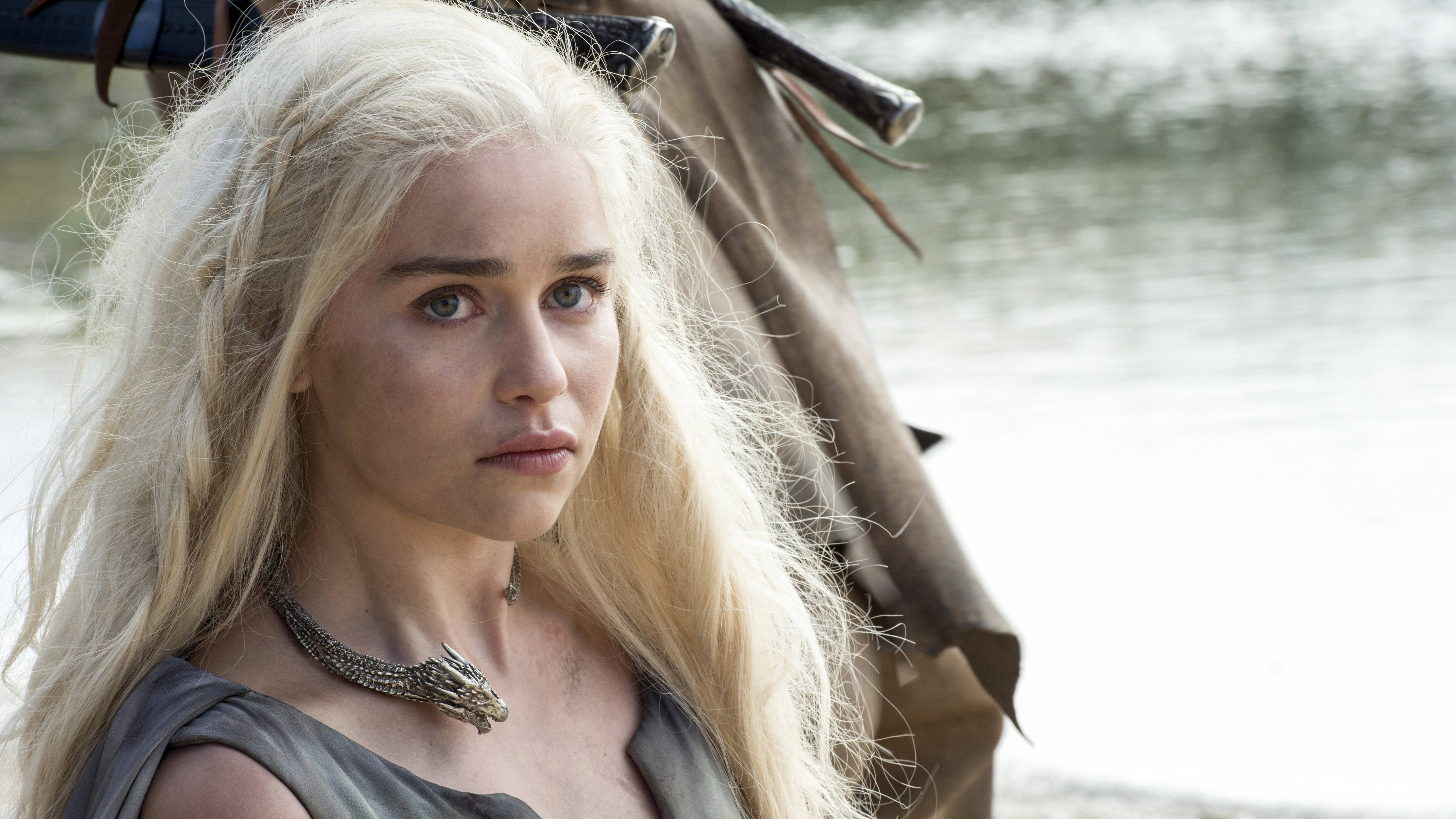 Emilia 桌布 壁紙 — 一位擁有長白金金色頭髮和龍骨項鍊的女人，在水邊的馬旁專注地凝視。