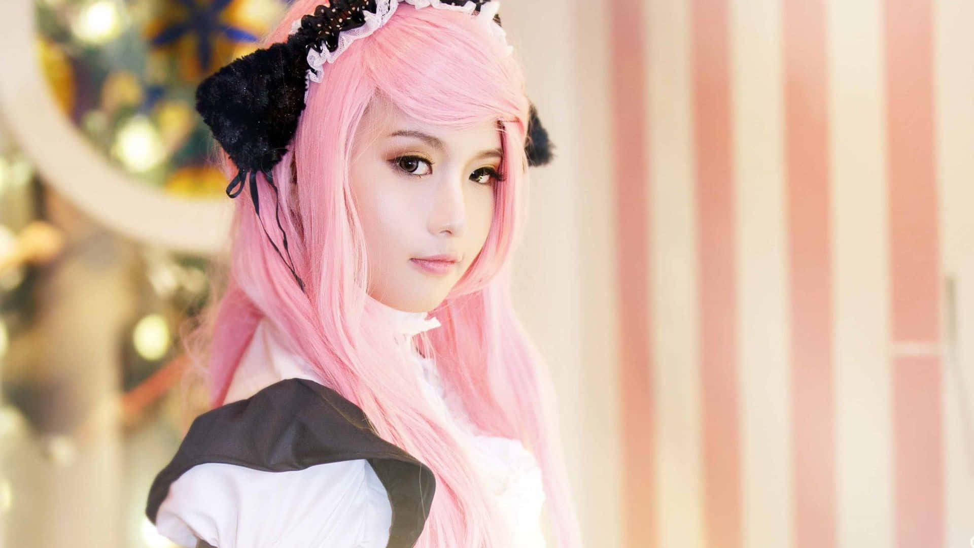 Cosplay Anime Kawaii 桌布 壁紙 — 一位擁有長粉紅頭髮和黑色貓耳的年輕女性，穿著女僕裝，背景是柔和的粉紅條紋。