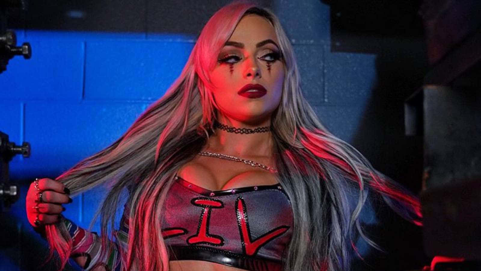 WWE 桌布 壁紙 — 一位擁有長銀色頭髮和紅色化妝的女性，在黑暗的工業環境中，在霓虹燈下戲劇性地擺姿勢。