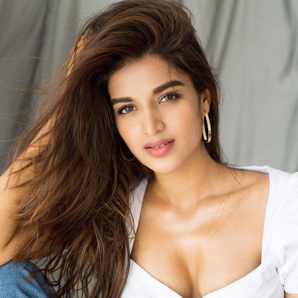 Telugu Heroines 桌布 壁紙 — 一位擁有長長棕色頭髮和金色耳環的女性，穿著白色上衣自信地凝視鏡頭。