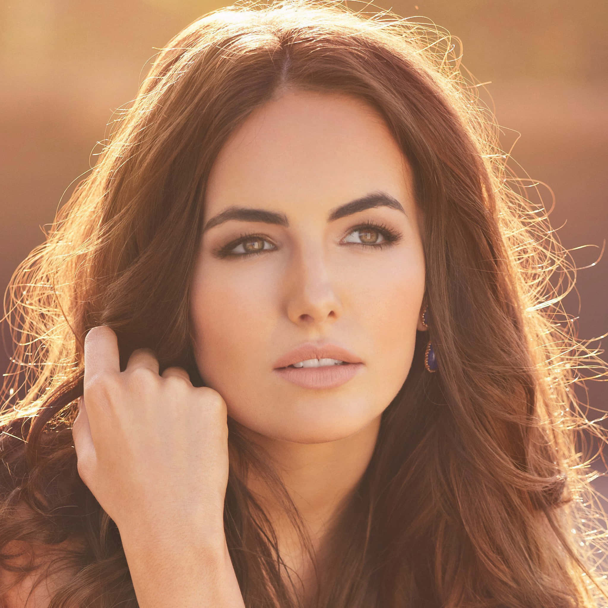 Camilla Belle 桌布 壁紙 — 一位擁有長長棕色頭髮的女性，在金色陽光凸顯她的髮絲和臉龐時，若有所思地凝視著。