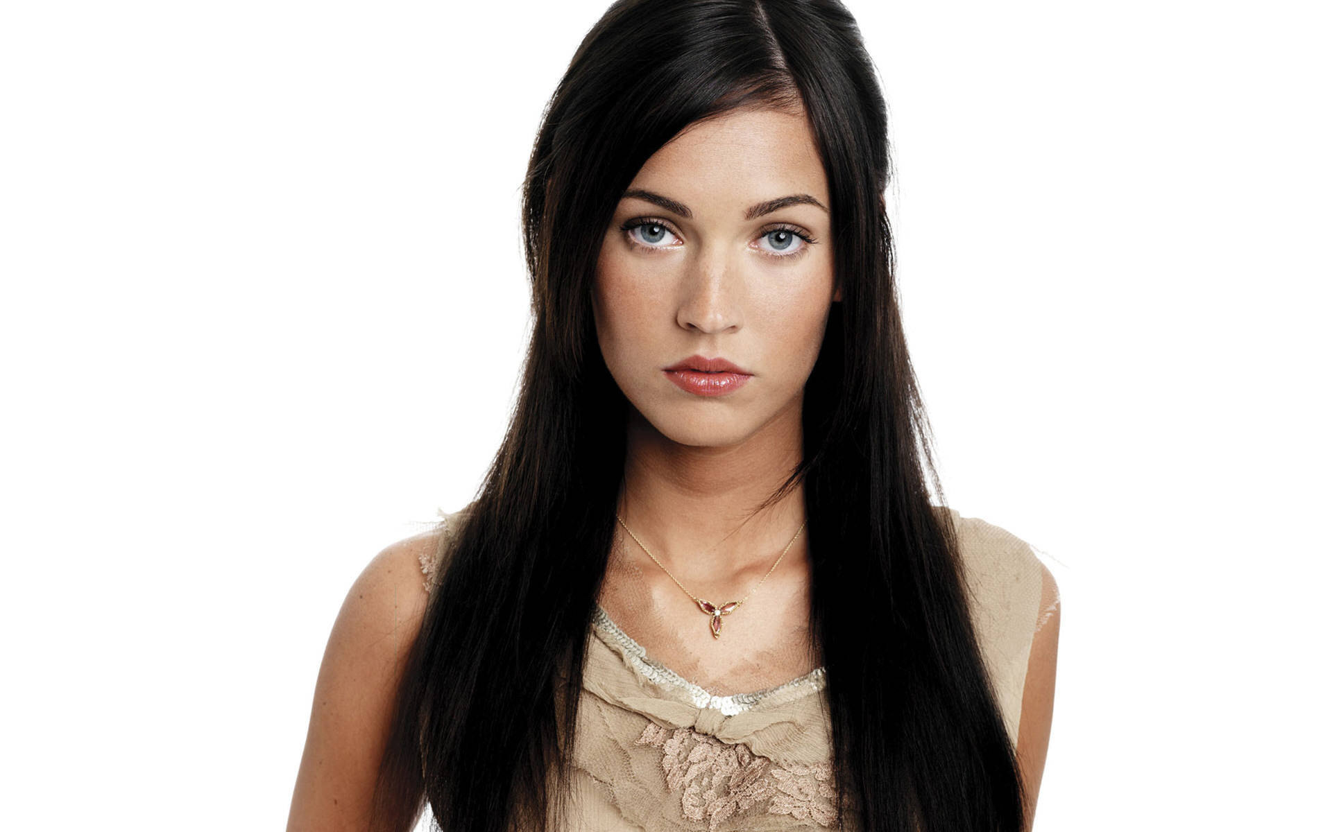 Megan Fox HD 桌布 壁紙 — 一位擁有長長黑髮和引人注目的藍眼睛的女性，在純白背景下直視鏡頭。