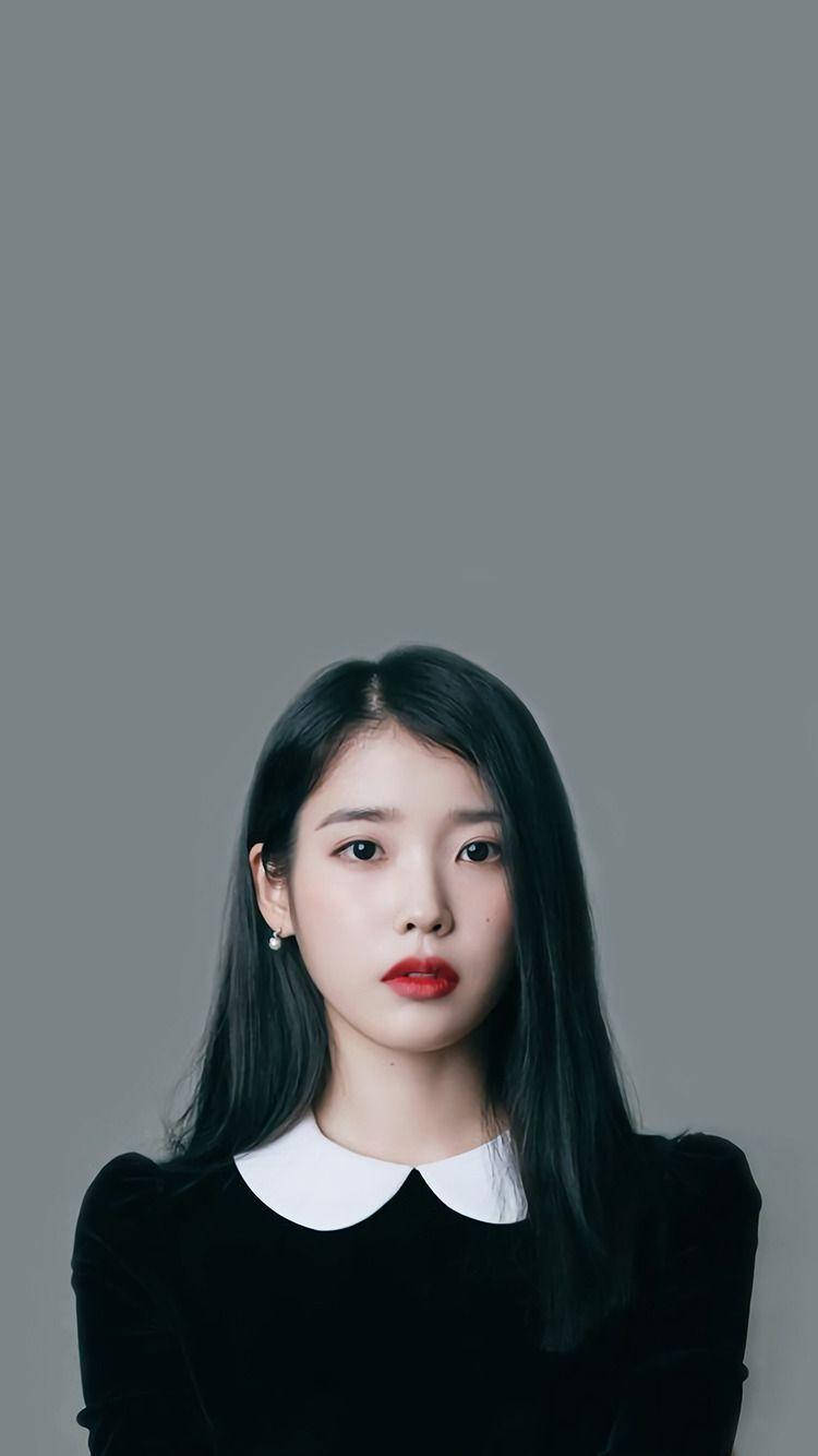 iu phone 桌布 壁紙 — 一位擁有長長黑髮和鮮豔紅唇的年輕女性，在純灰色背景下直視鏡頭。