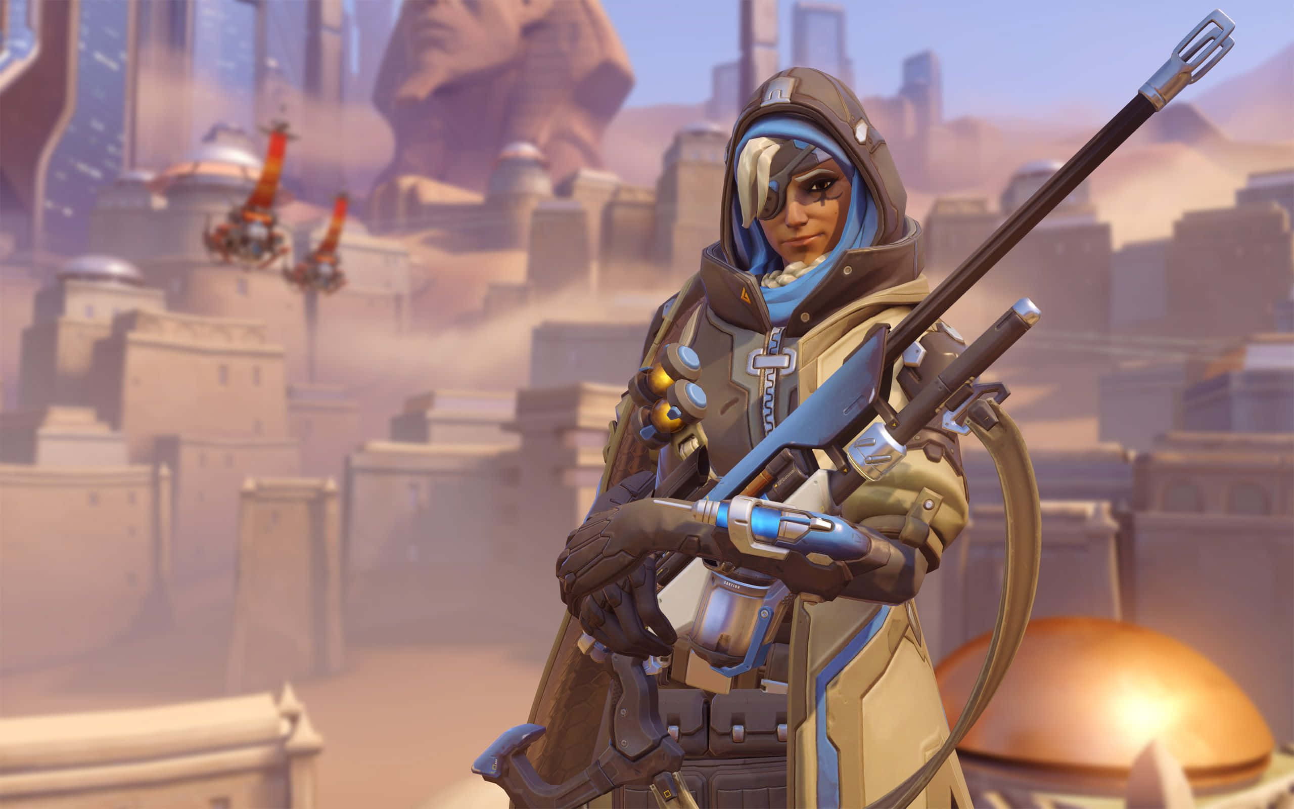 Overwatch Ana 桌布 壁紙 — 一位擁有電子眼的未來戰士，在沙漠城市景觀背景下手持狙擊步槍。