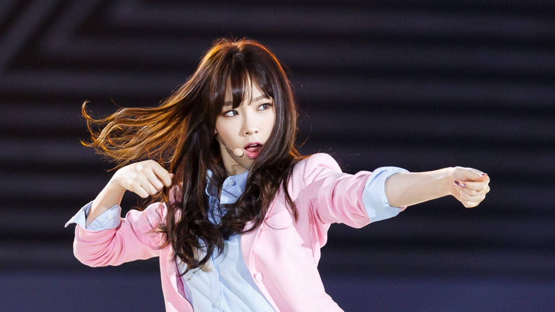 태연 桌布 壁紙 — 一位擁有飄逸棕色長髮的女表演者在舞台燈光下穿著粉紅色西裝外套動感起舞。
