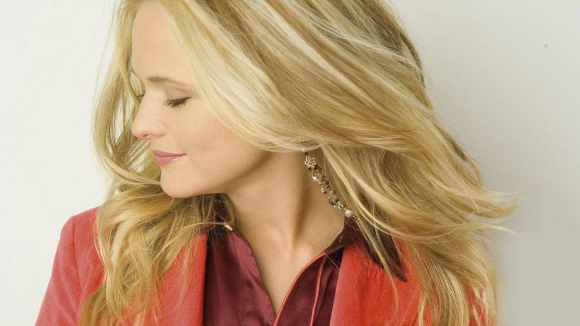 Miranda Lambert 桌布 壁紙 — 一位擁有飄逸金髮和紅色襯衫的女性，在純白背景下帶著平靜的表情向下凝視。