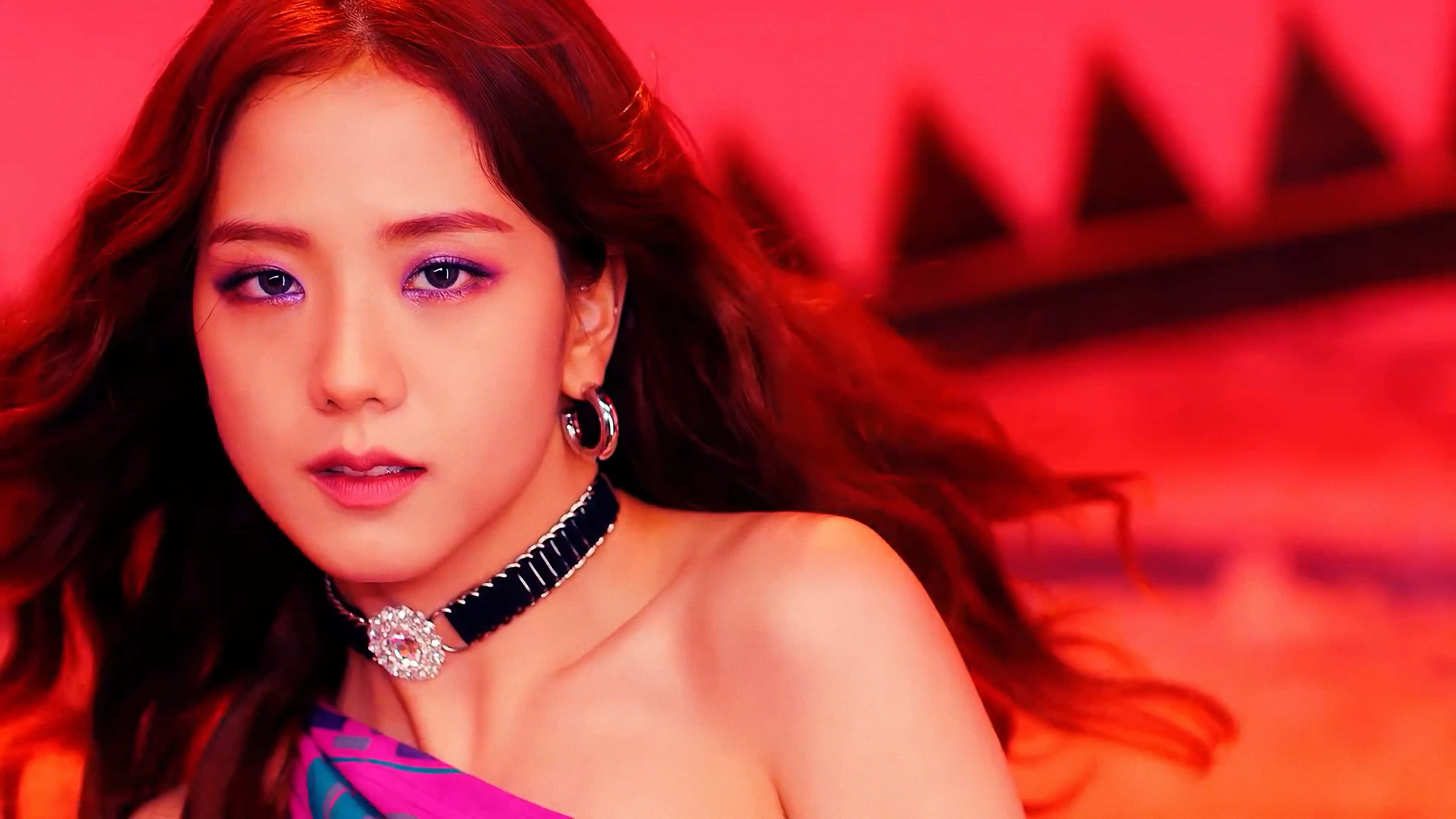 BLACKPINK 桌布 壁紙 — 一位擁有飄逸長髮和濃妝豔抹的女性，在帶有幾何陰影的鮮紅色背景下凝視著。
