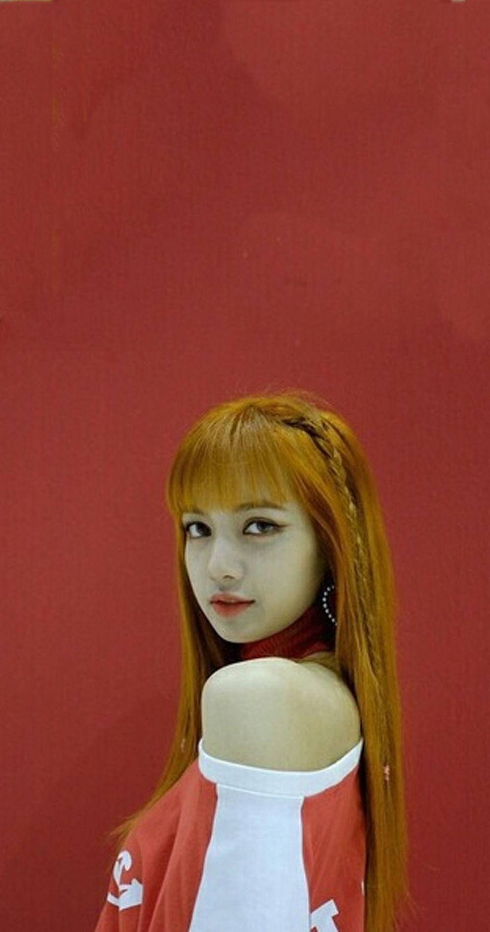 橙色頭髮的年輕女性在紅色牆前穿著紅白上衣。 — BLACKPINK Lisa GIF 壁紙
