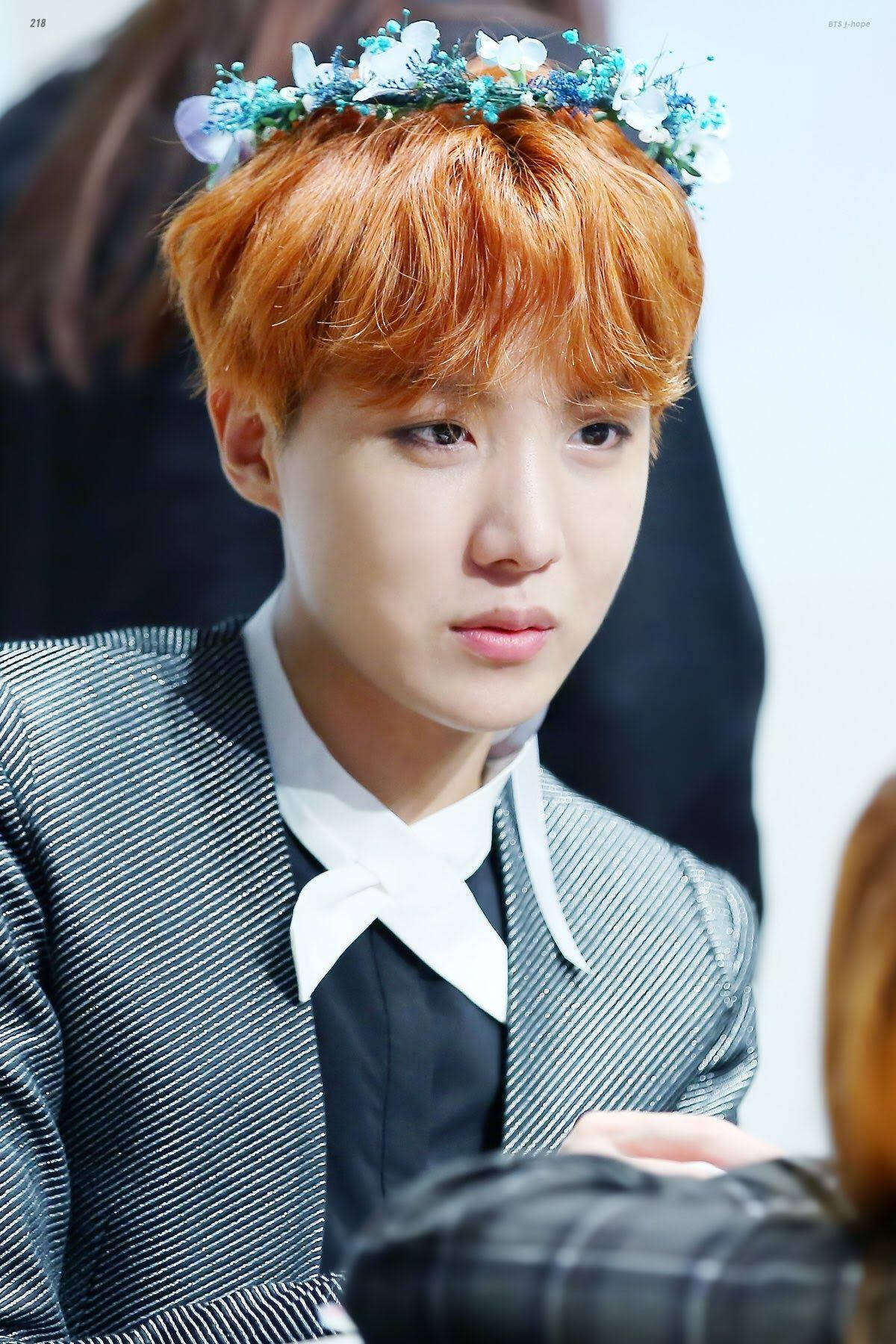 jhope 桌布 壁紙 — 一位擁有鮮豔橙色頭髮的年輕男子戴著花冠，穿著條紋西裝和白色領結。