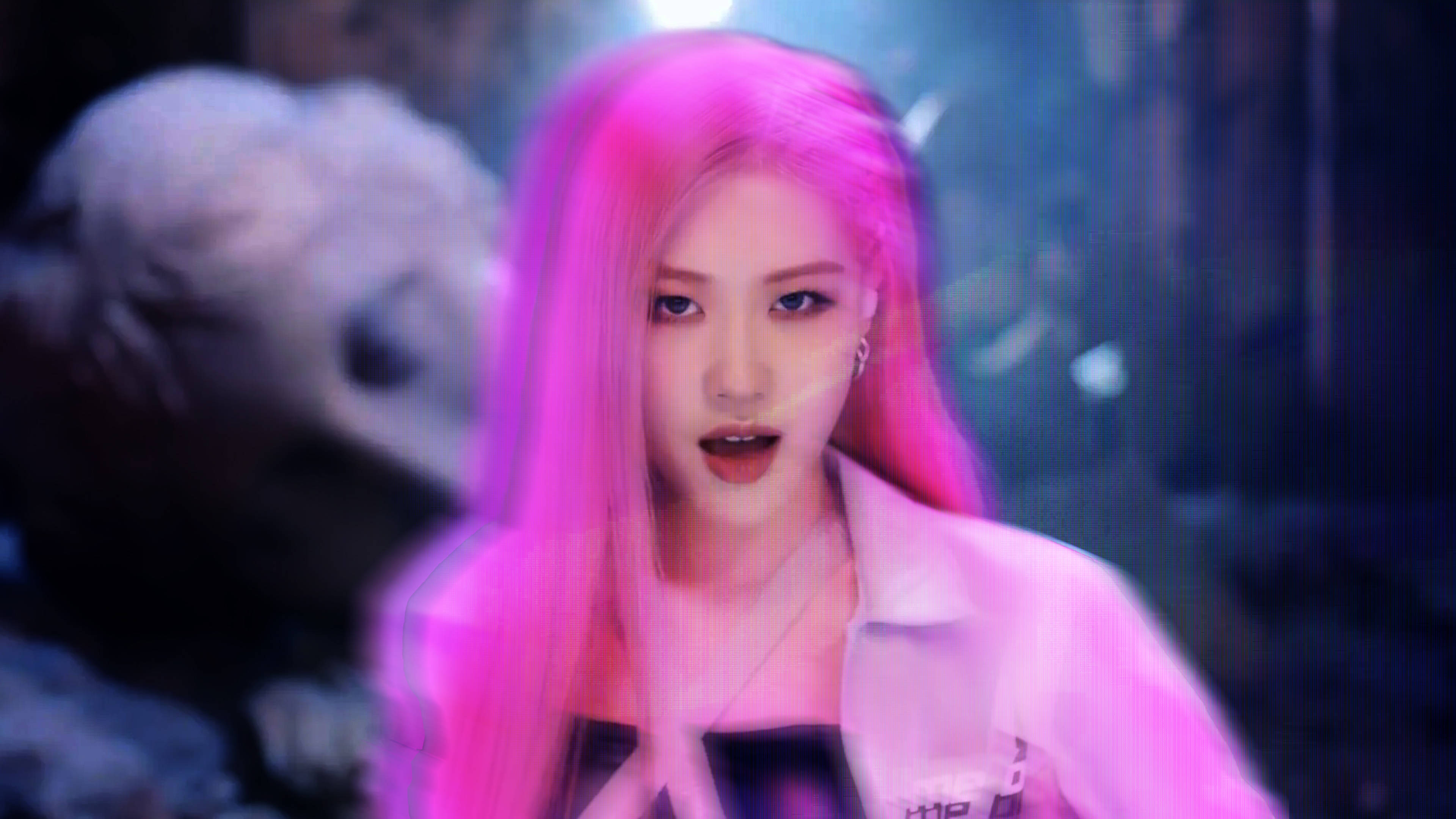 Rose Blackpink 桌布 壁紙 — 一位擁有鮮豔粉紅色頭髮的女性在黑暗、陰鬱的城市環境中，在霓虹燈下強烈地凝視。