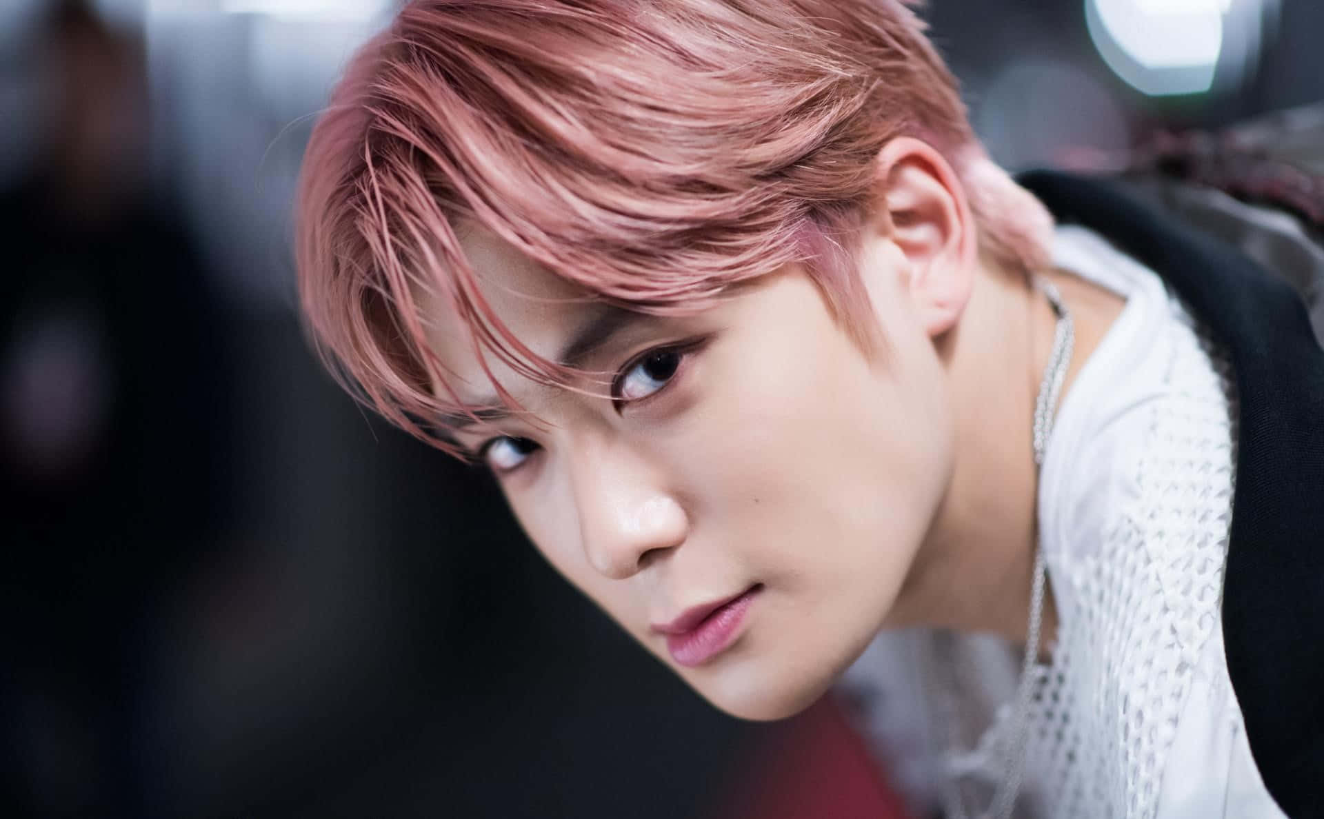 Kpop Aesthetic 桌布 壁紙 — 一位擁有鮮豔粉紅色頭髮的年輕男子的特寫肖像，他正專注地看著鏡頭。