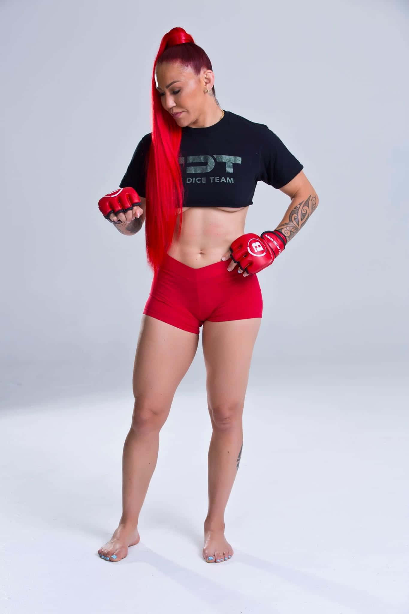 UFC 桌布 壁紙 — 一位擁有鮮豔紅髮和手套的女戰士，在工作室中自信地擺姿勢，背景是純白色。