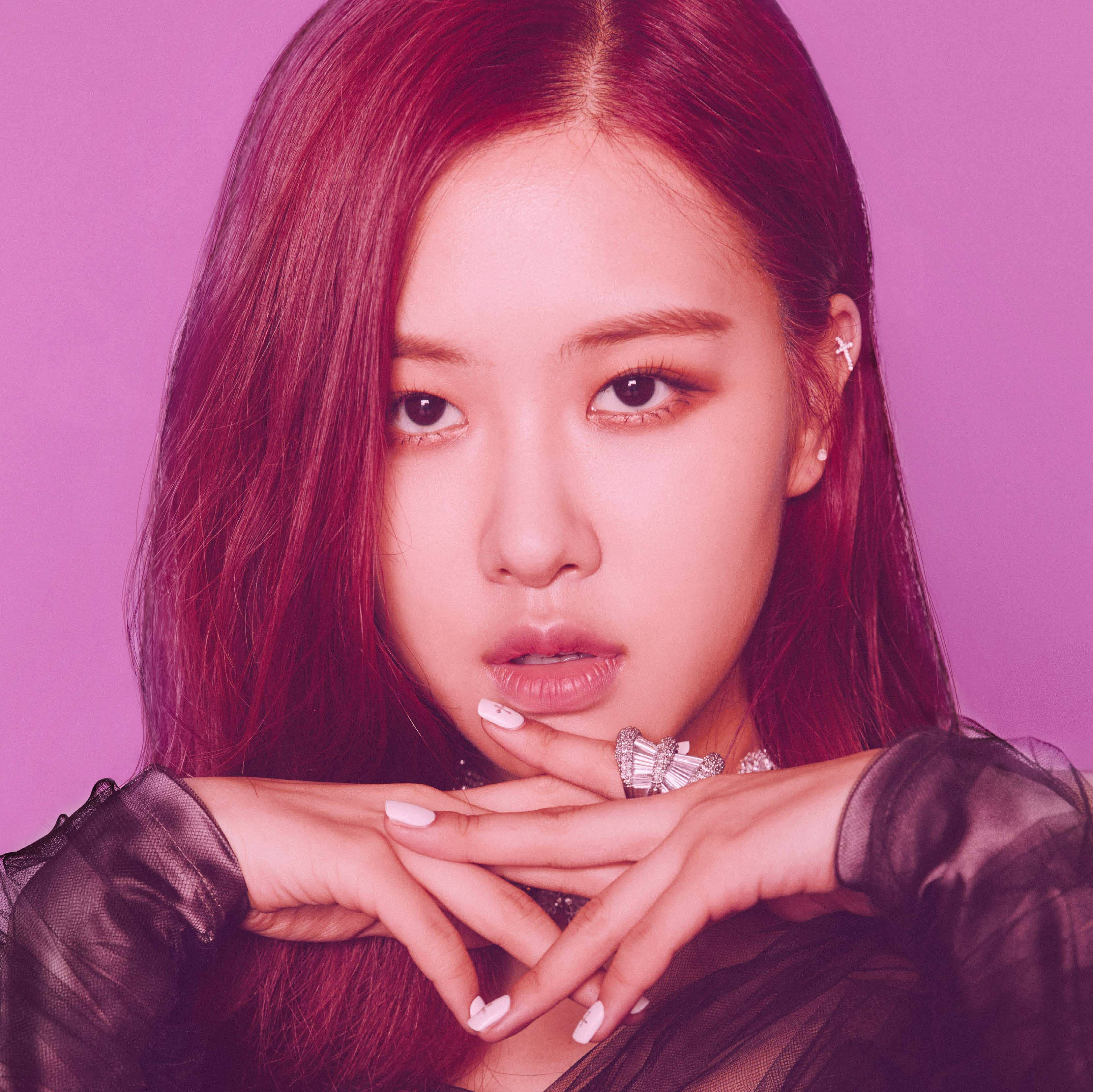 BLACKPINK 桌布 壁紙 — 一位擁有鮮豔紅髮和白指甲的女性，在純粉紅色背景前擺姿勢，雙手交疊在下巴下方。