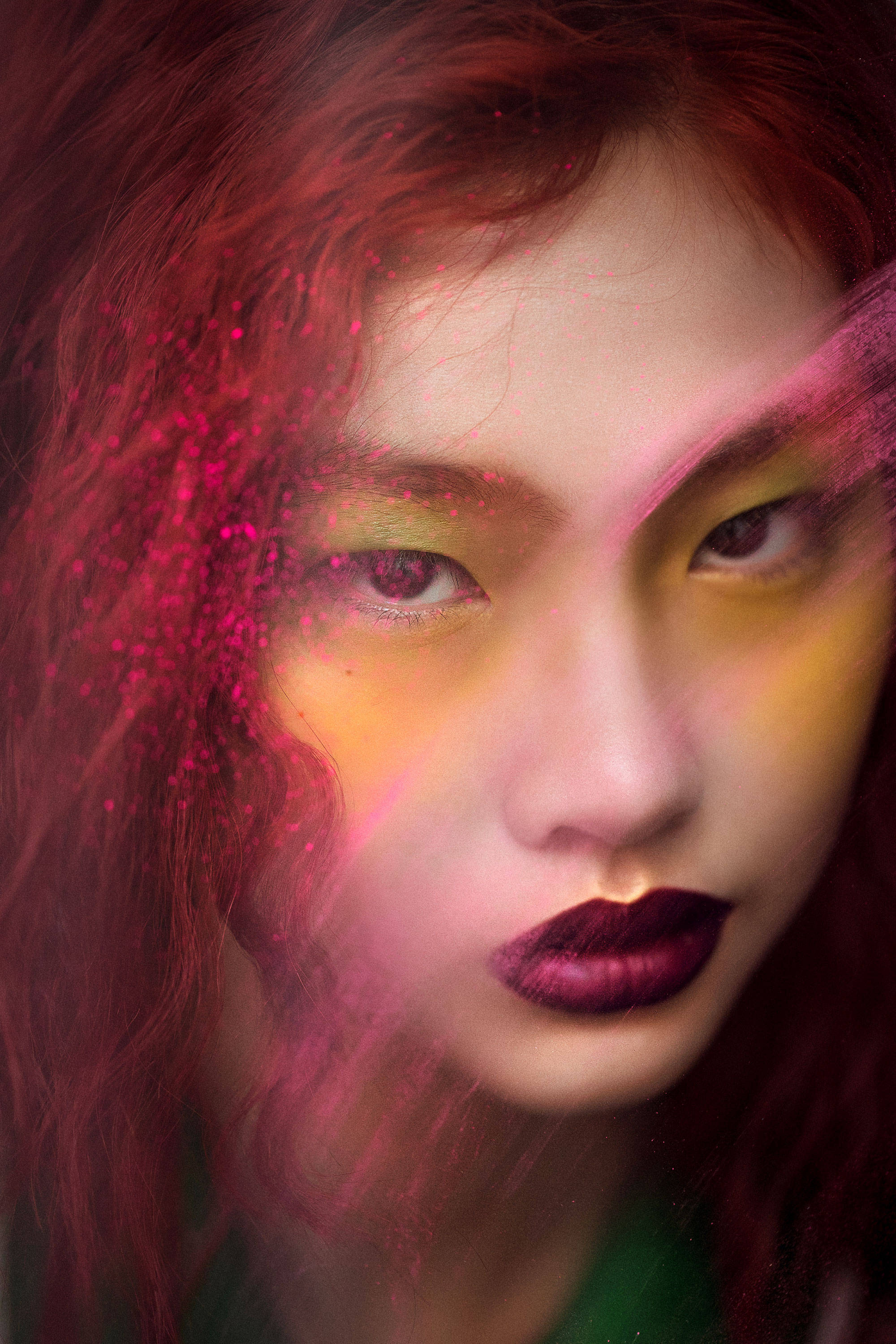 Hoyeon 桌布 壁紙 — 一位擁有鮮豔紅髮和誇張妝容的女性的特寫肖像，她的臉部部分被發光的粉紅色和黃色光效遮蓋。