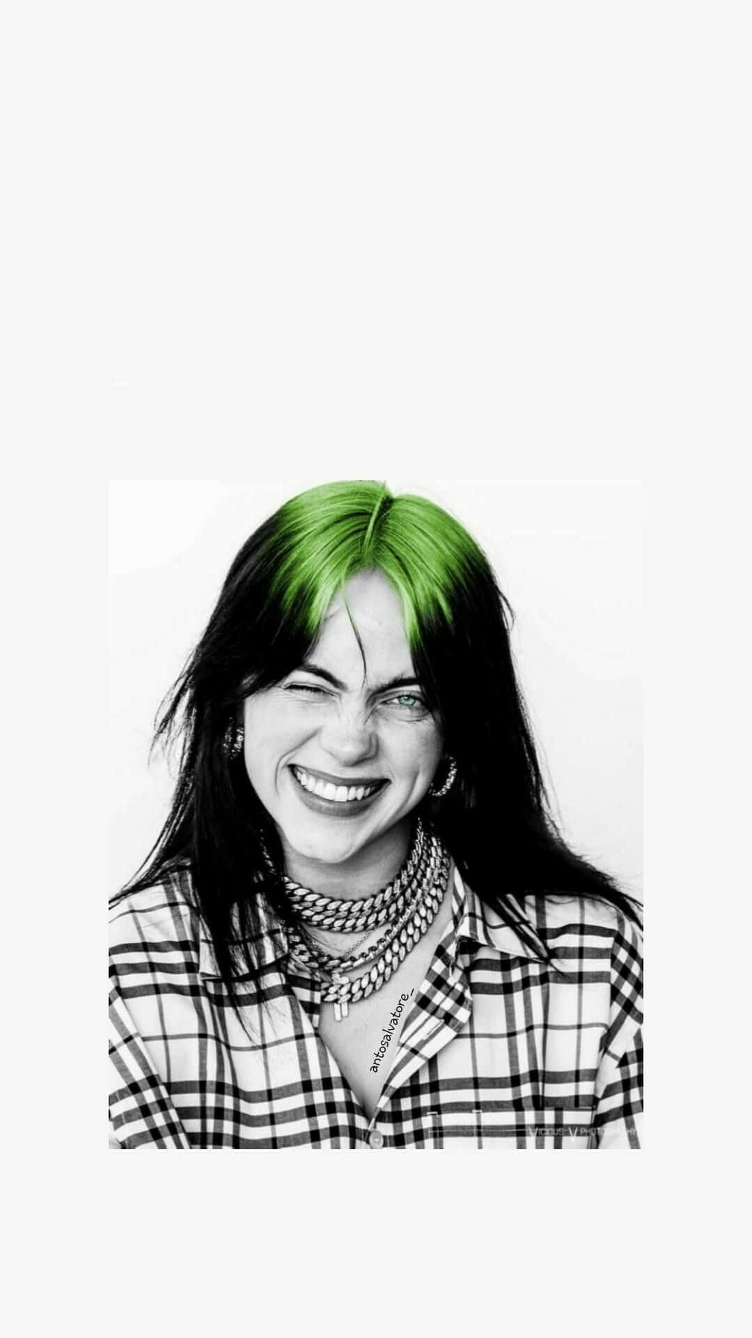 Billie Eilish 2021 桌布 壁紙 — 一位擁有鮮豔綠髮的女性，戴著多層鏈條和格紋襯衫，眨眼並燦爛微笑的肖像。