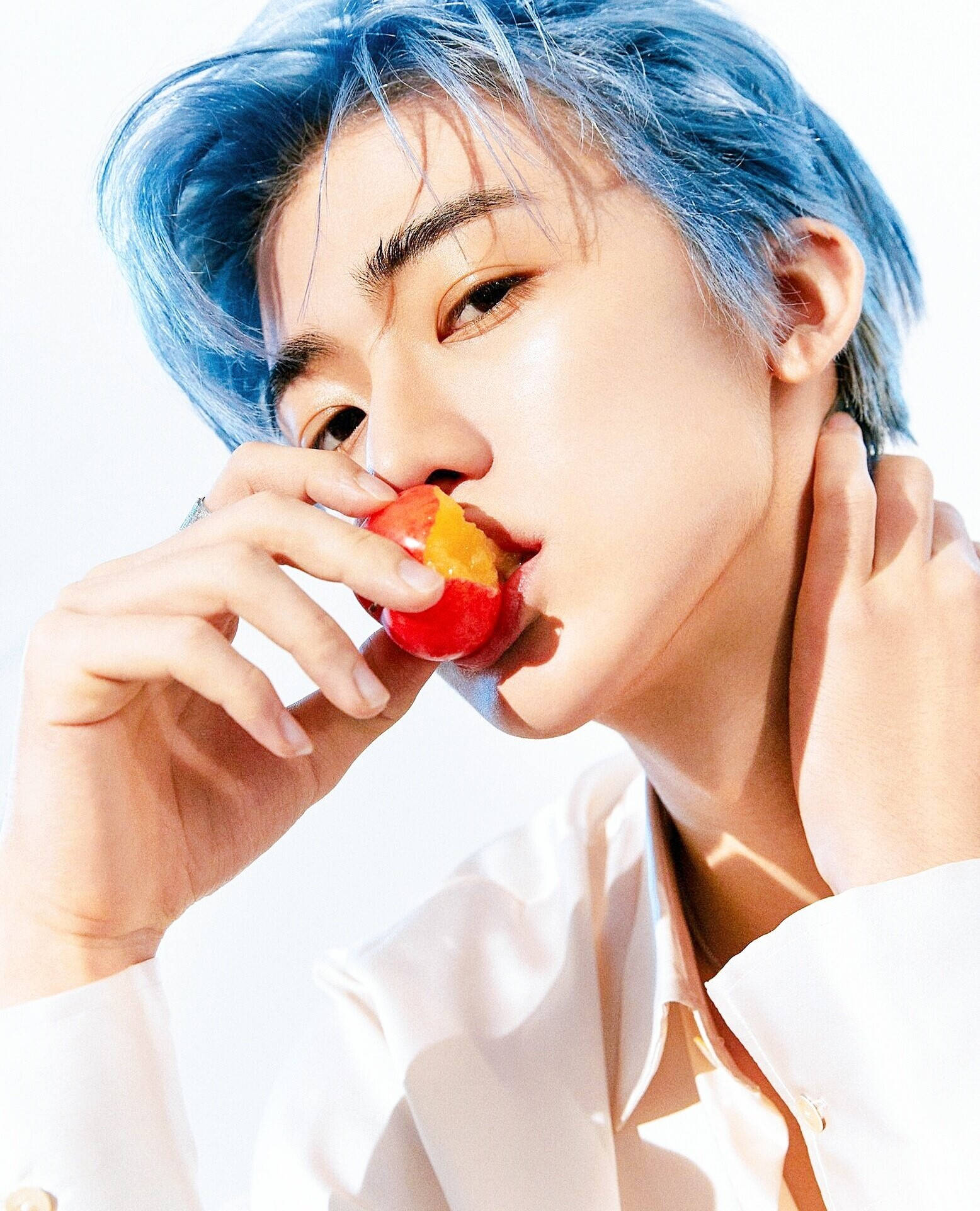 jaemin 桌布 壁紙 — 一位擁有鮮豔藍色頭髮的年輕男子，在純白背景上咬著一顆鮮紅的櫻桃。