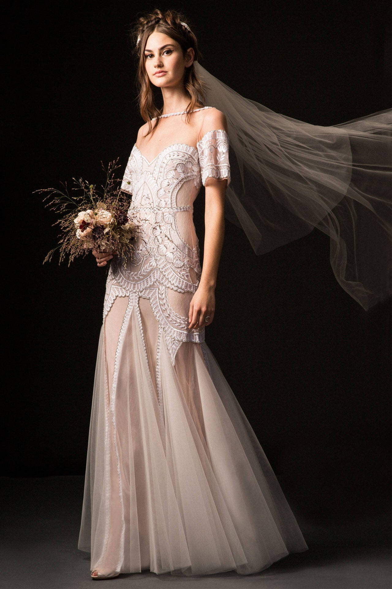 Bride 桌布 壁紙 — 一位新娘穿著華麗的露肩蕾絲禮服，手持鄉村風格的花束，頭紗在深色攝影棚背景下飄逸。
