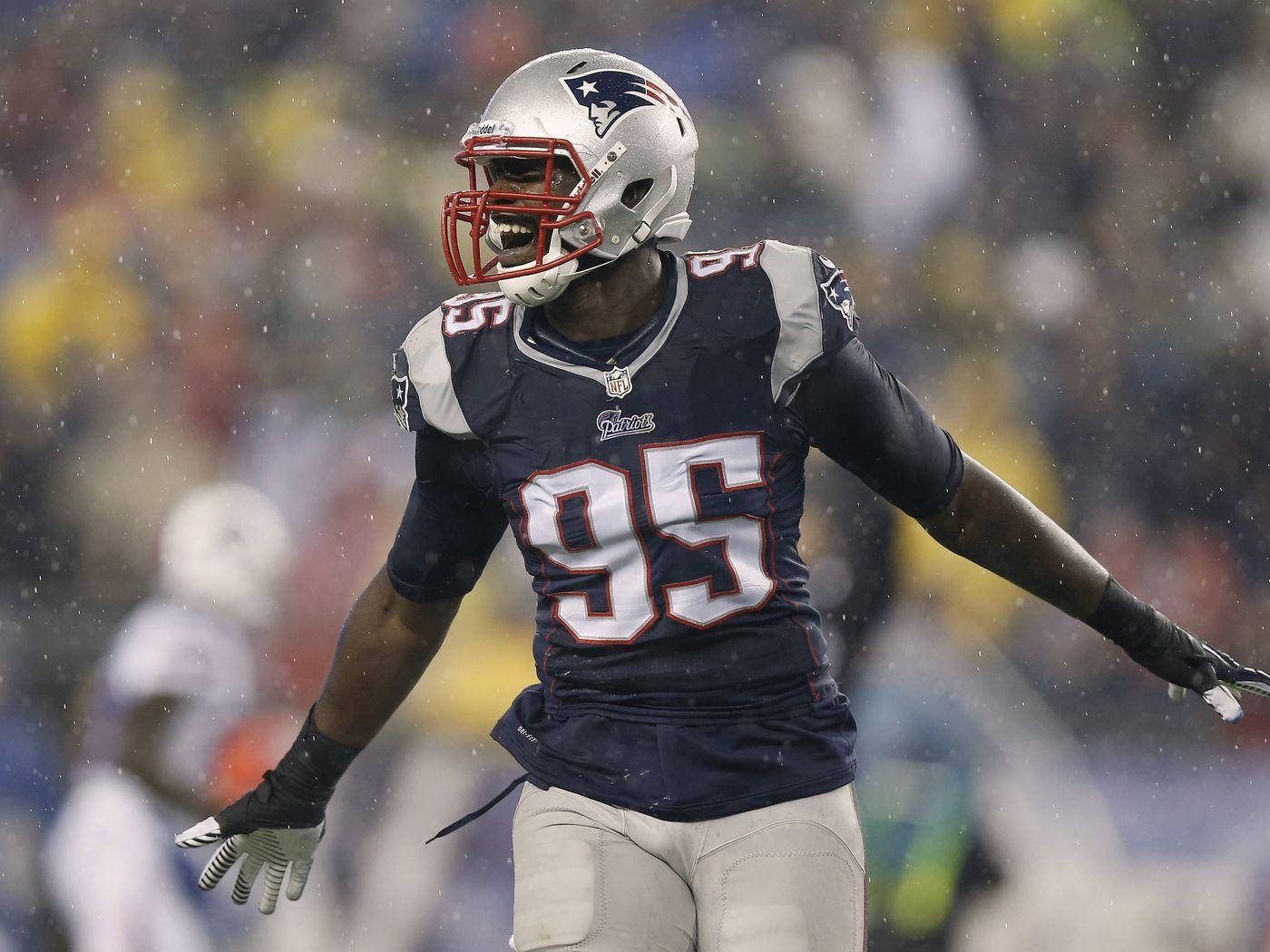 New England Patriots 桌布 壁紙 — 一位新英格蘭愛國者隊的美式足球員身穿海軍藍球衣（95號）在雨中球場張開雙臂慶祝。