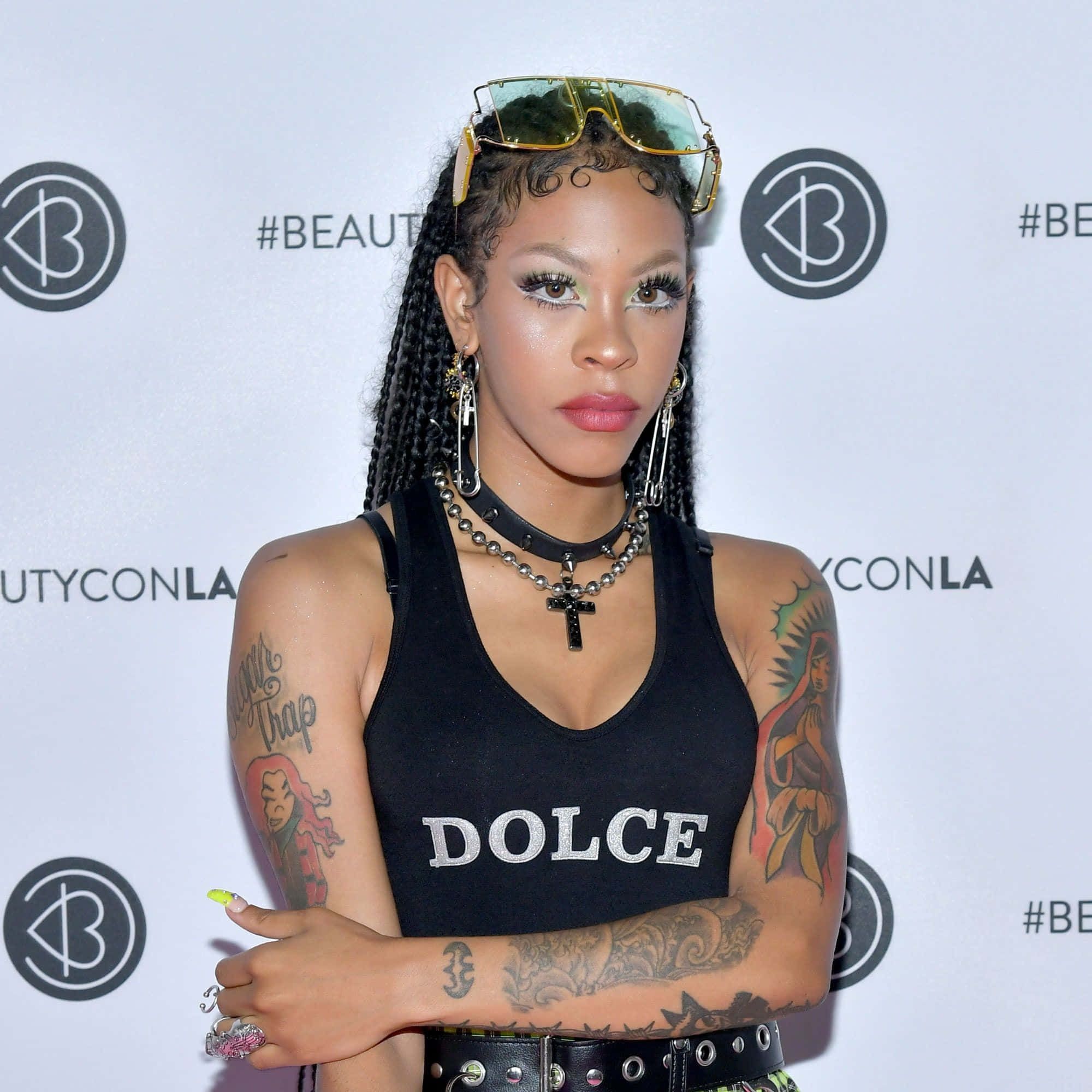 Rico Nasty 桌布 壁紙 — 一位時尚女性，編著辮子，帶有醒目紋身，在BeautyConLA活動中自信地穿著黑色Dolce背心擺姿勢。