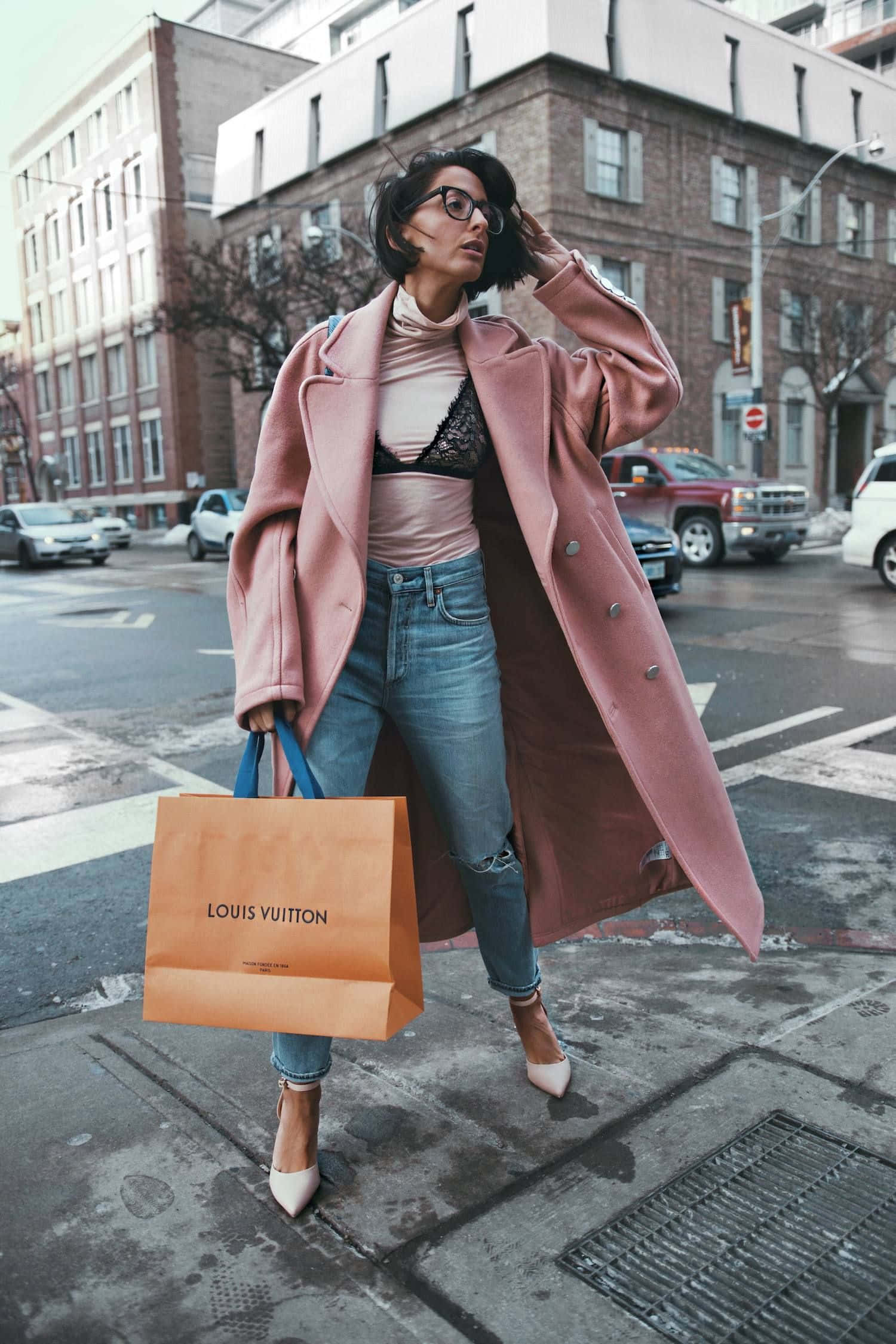 Pink Coat 桌布 壁紙 — 一位時尚女性穿著粉紅色外套和眼鏡，站在城市人行道上，手持路易威登手袋。