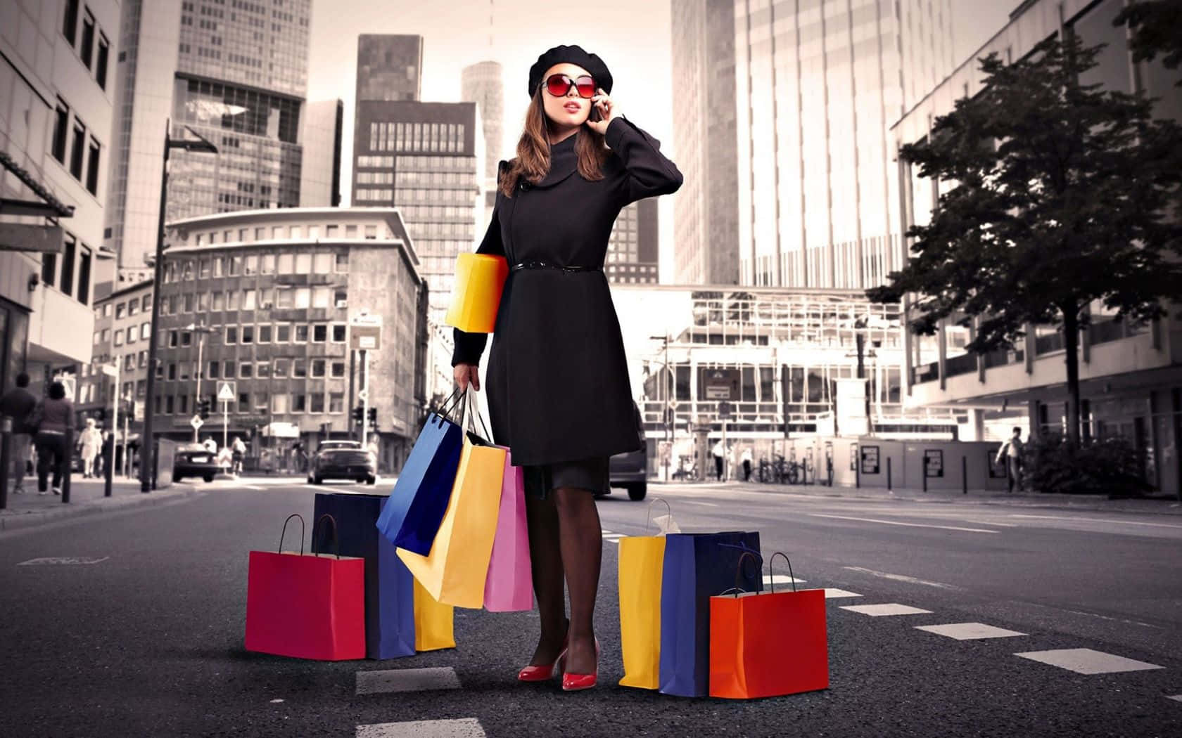 Shopping 桌布 壁紙 — 一位時尚女性身穿黑色外套和紅色高跟鞋，站在城市街道上，手持色彩繽紛的購物袋，同時正在講電話。