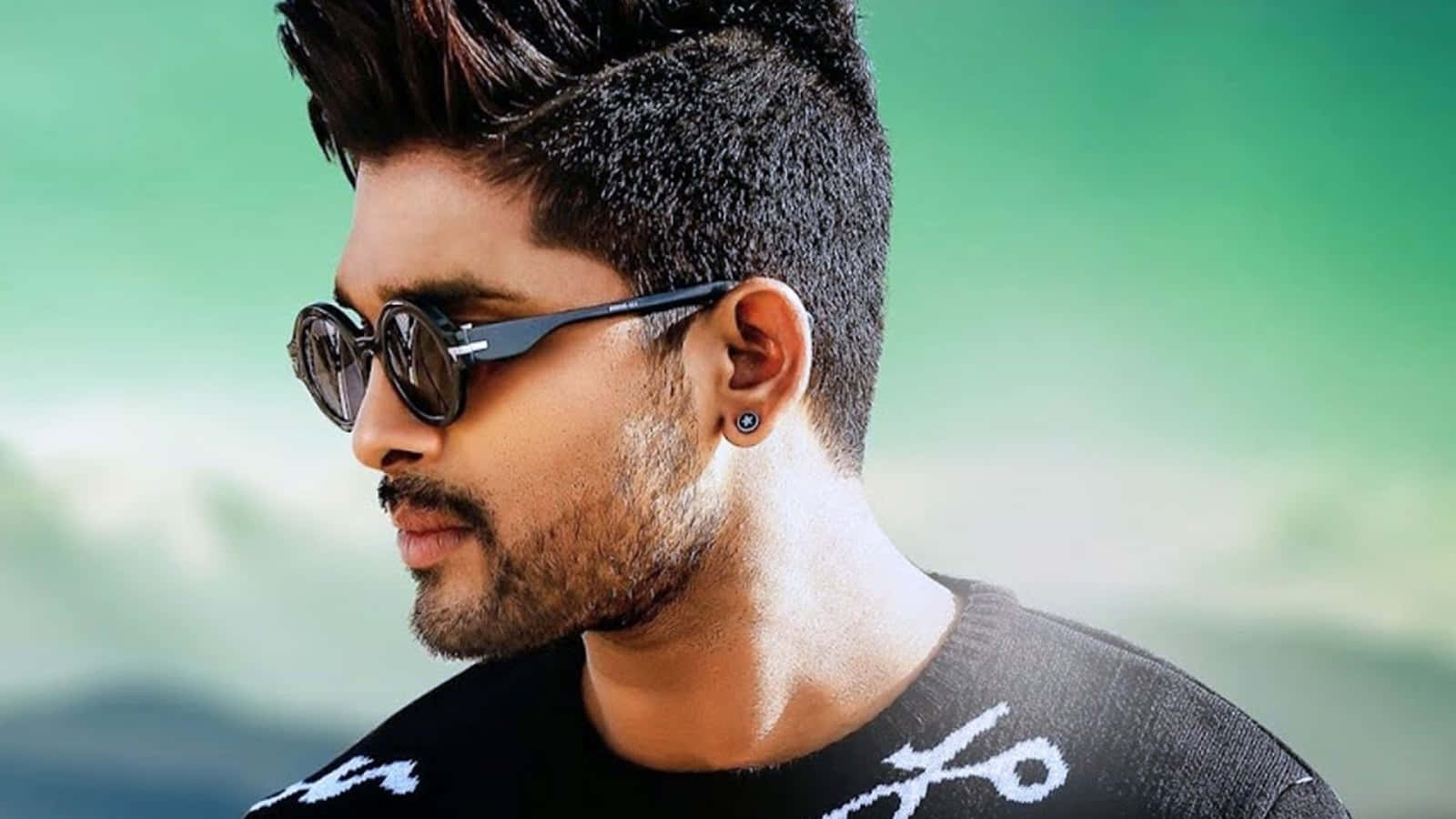 Allu Arjun 桌布 壁紙 — 一位時尚男士，留著俐落的髮型，戴著圓形太陽眼鏡，在柔和的綠色模糊背景前若有所思地凝視。