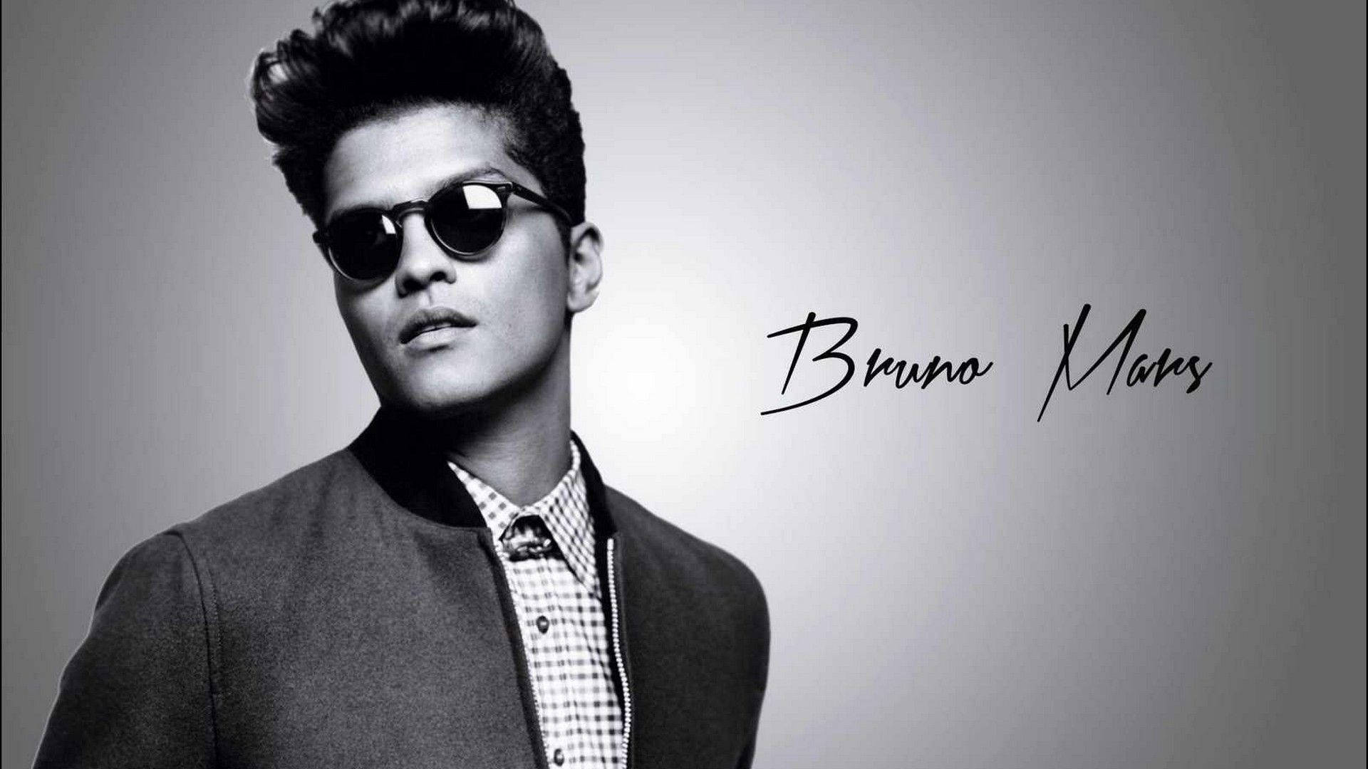 Bruno Mars 桌布 壁紙 — 一位時尚男士梳著蓬巴杜髮型，戴著太陽眼鏡，在單色工作室肖像中自信地擺姿勢。