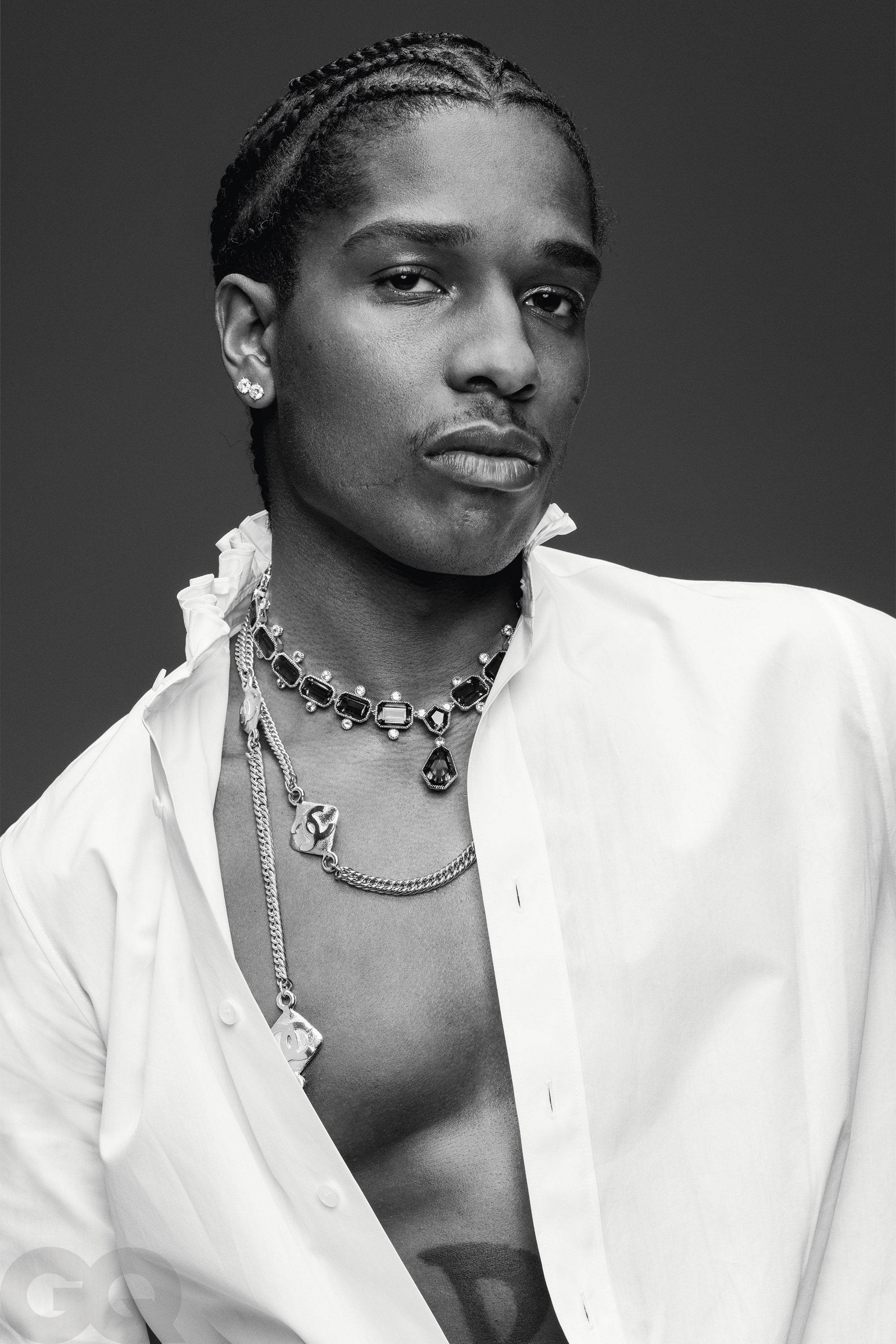 rocky 桌布 壁紙 — 一位時尚男士的黑白肖像，他編著辮子頭髮，佩戴多層珠寶，身穿敞開的白色襯衫。