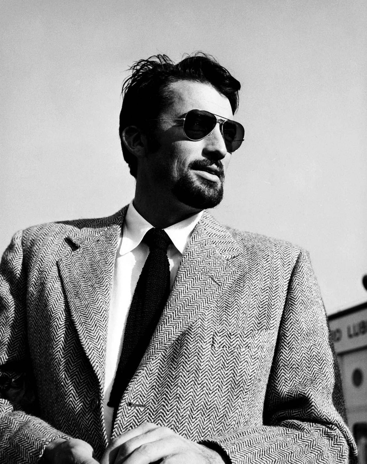 actor 桌布 壁紙 — 一位時尚男士穿著人字紋西裝和飛行員太陽眼鏡，在樸素的天空下自信地凝視。