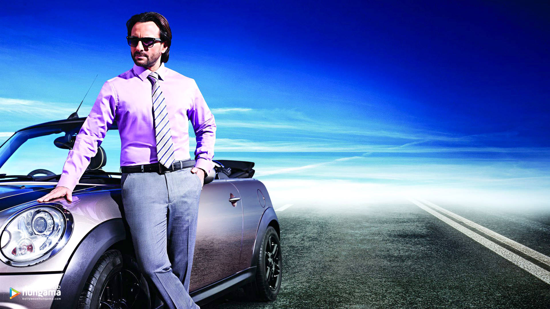 Saif Ali Khan 桌布 壁紙 — 一位時尚男士穿著紫色襯衫和領帶，在開闊的道路上自信地靠在一輛銀色敞篷車上，背景是充滿活力的藍天。