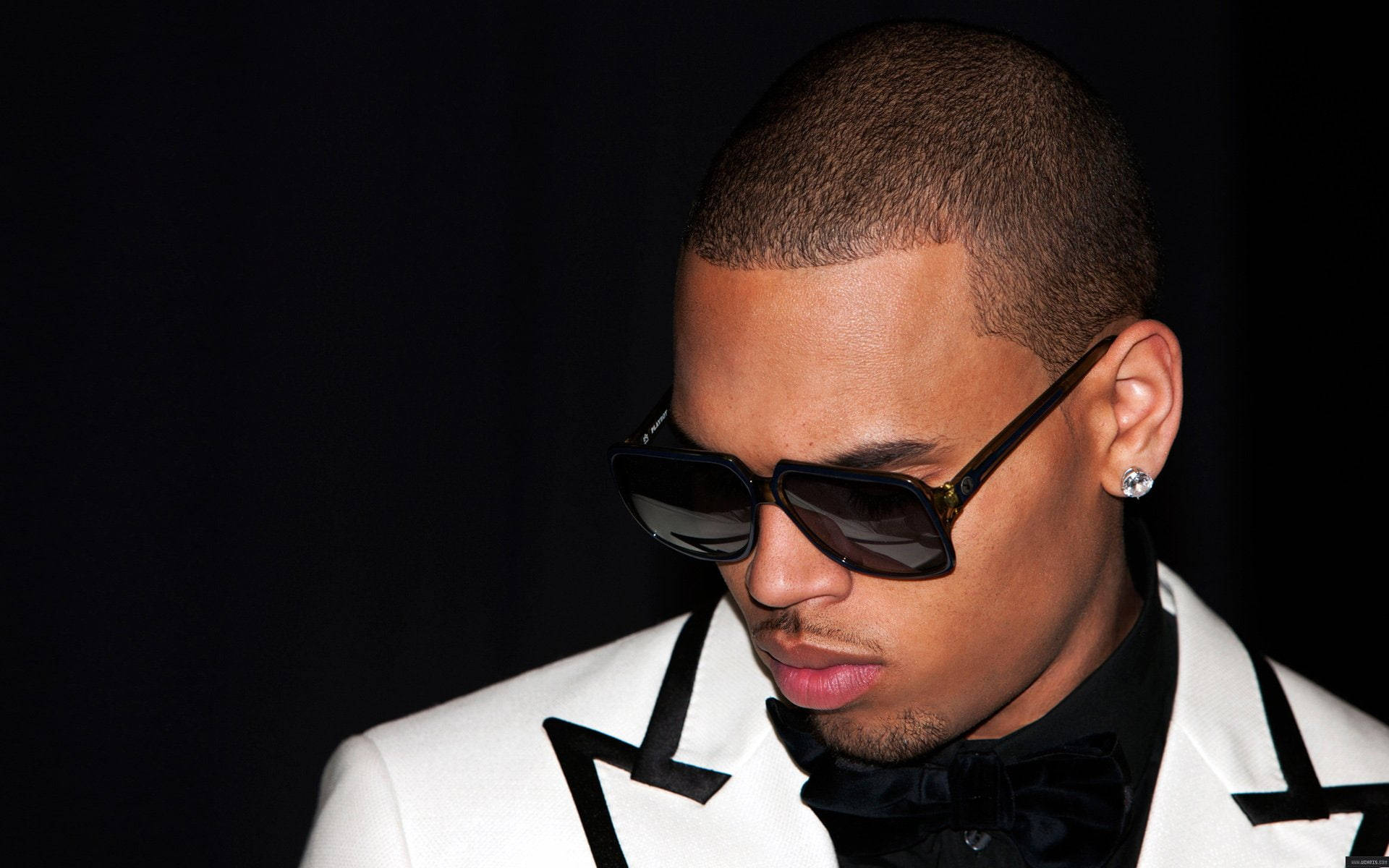 Chris Brown 桌布 壁紙 — 一位時尚男士身穿白色燕尾服，搭配黑色飾邊和太陽眼鏡，在深色背景前擺姿勢。