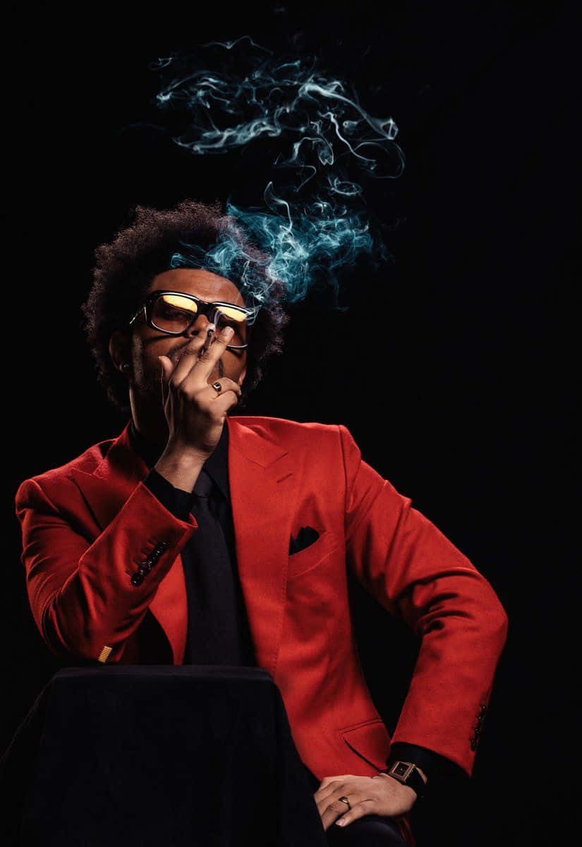 身穿紅色西裝、戴著太陽眼鏡的男士在昏暗的攝影棚中呼出藍色煙霧。