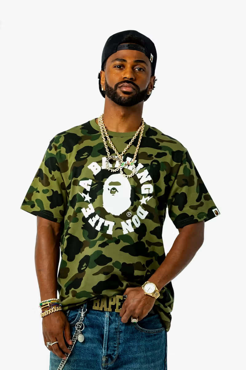 Bape 動態 桌布 壁紙 — 一位時尚男士身穿迷彩Bape T恤和金色鏈條，在純白背景前自信擺姿勢。