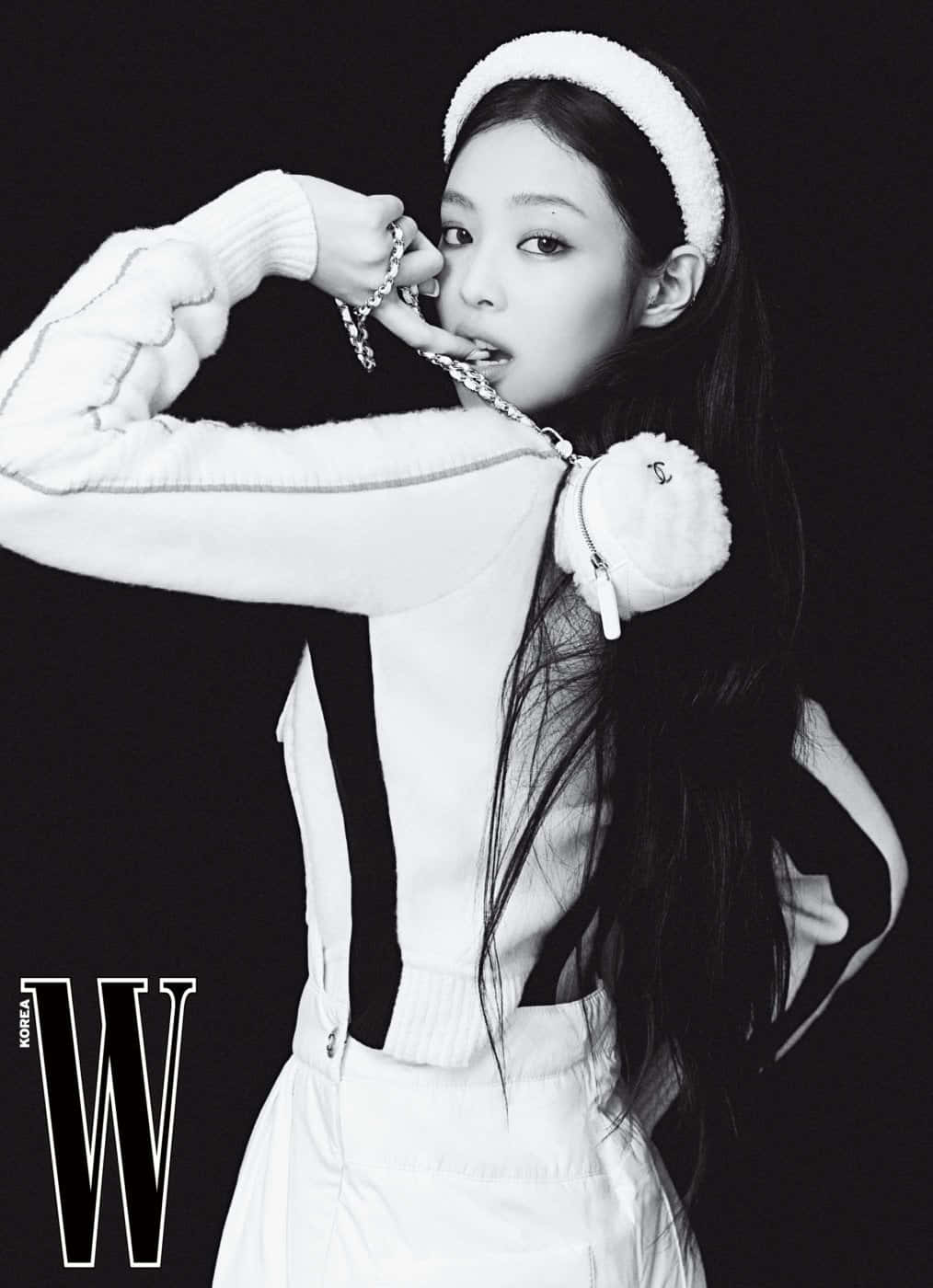 BLACKPINK 桌布 壁紙 — 一位時尚的女性以單色造型在黑色背景前自信地擺姿勢，戴著白色頭帶和服裝，配以鏈條飾品。