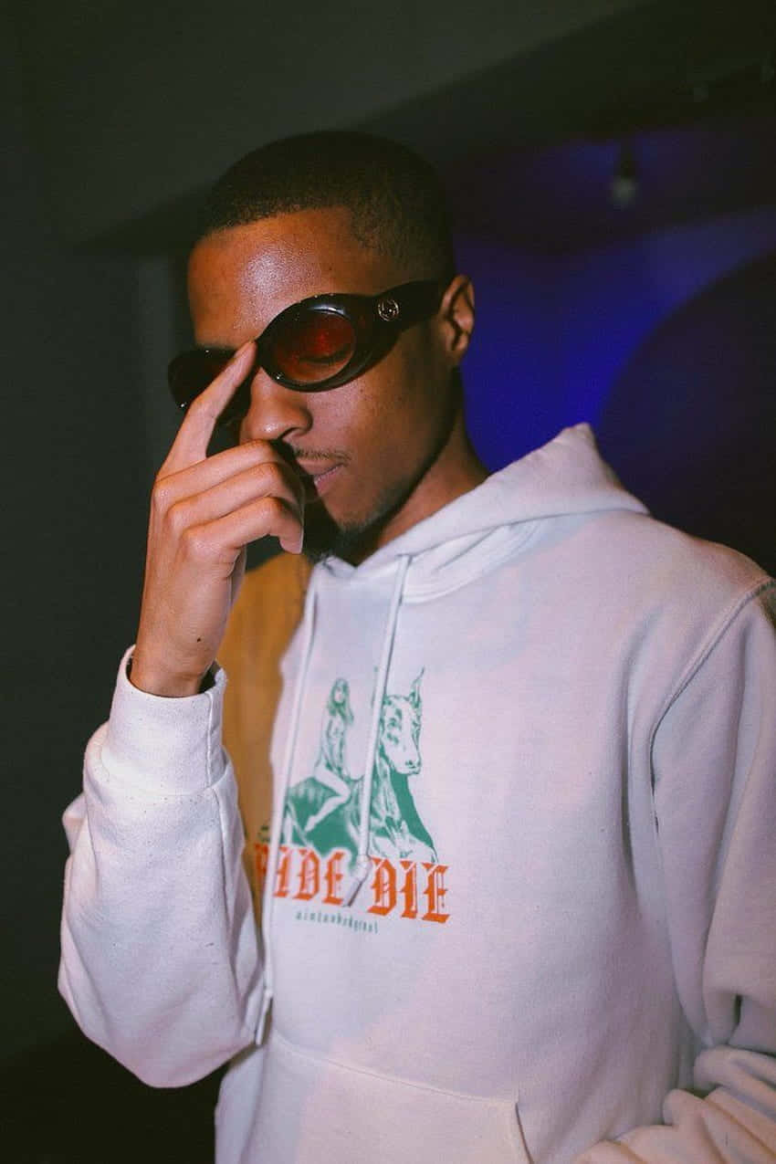 Pierre Bourne 桌布 壁紙 — 一位時尚的年輕男子穿著白色連帽衫和紅色太陽眼鏡，在一個光線昏暗、帶有藍色環境照明的房間裡調整眼鏡。