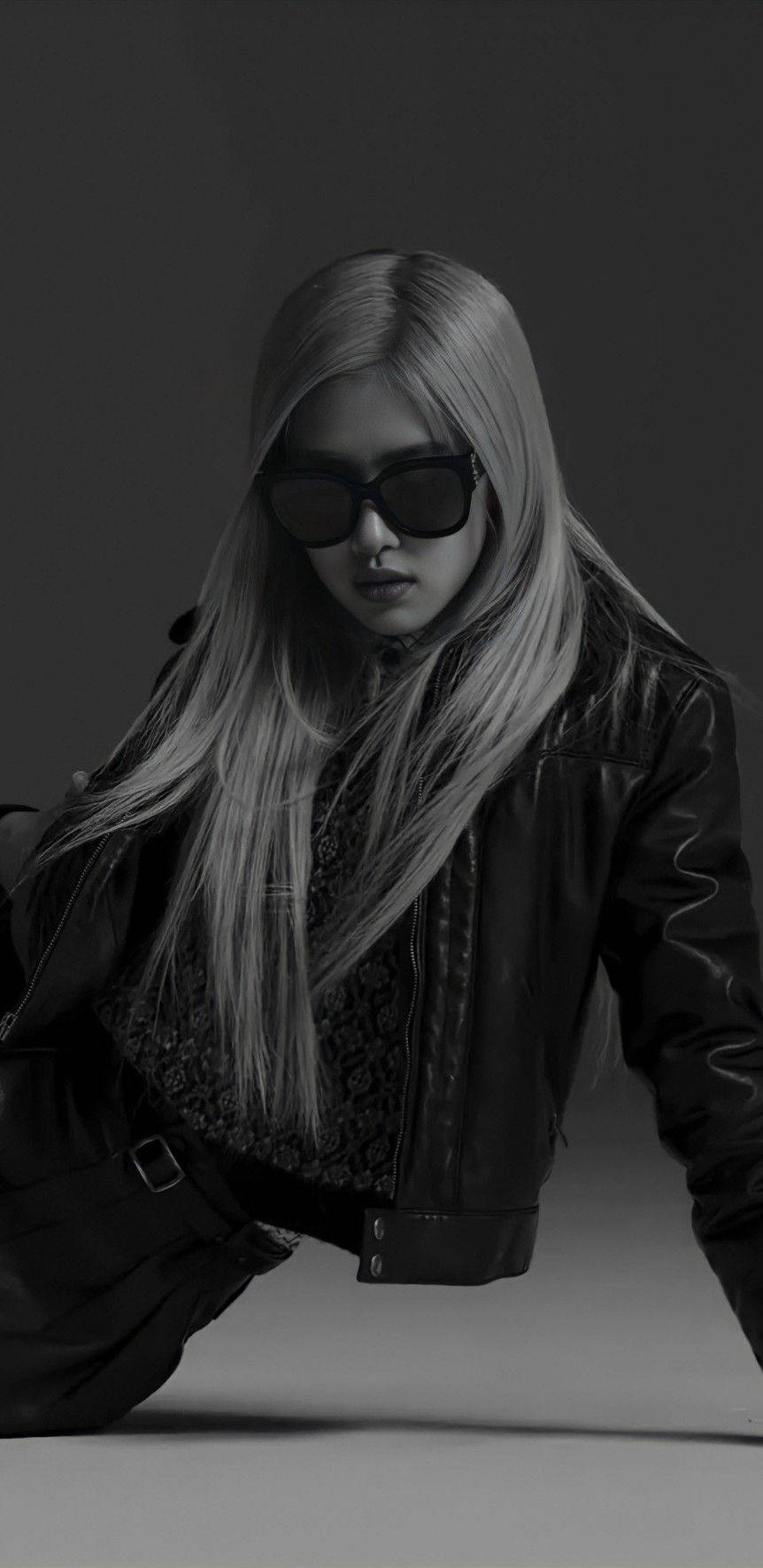 Sunglasses 桌布 壁紙 — 一位時尚的長髮金髮女性，戴著超大太陽眼鏡和皮夾克，在黑白工作室肖像中展現憂鬱氛圍。