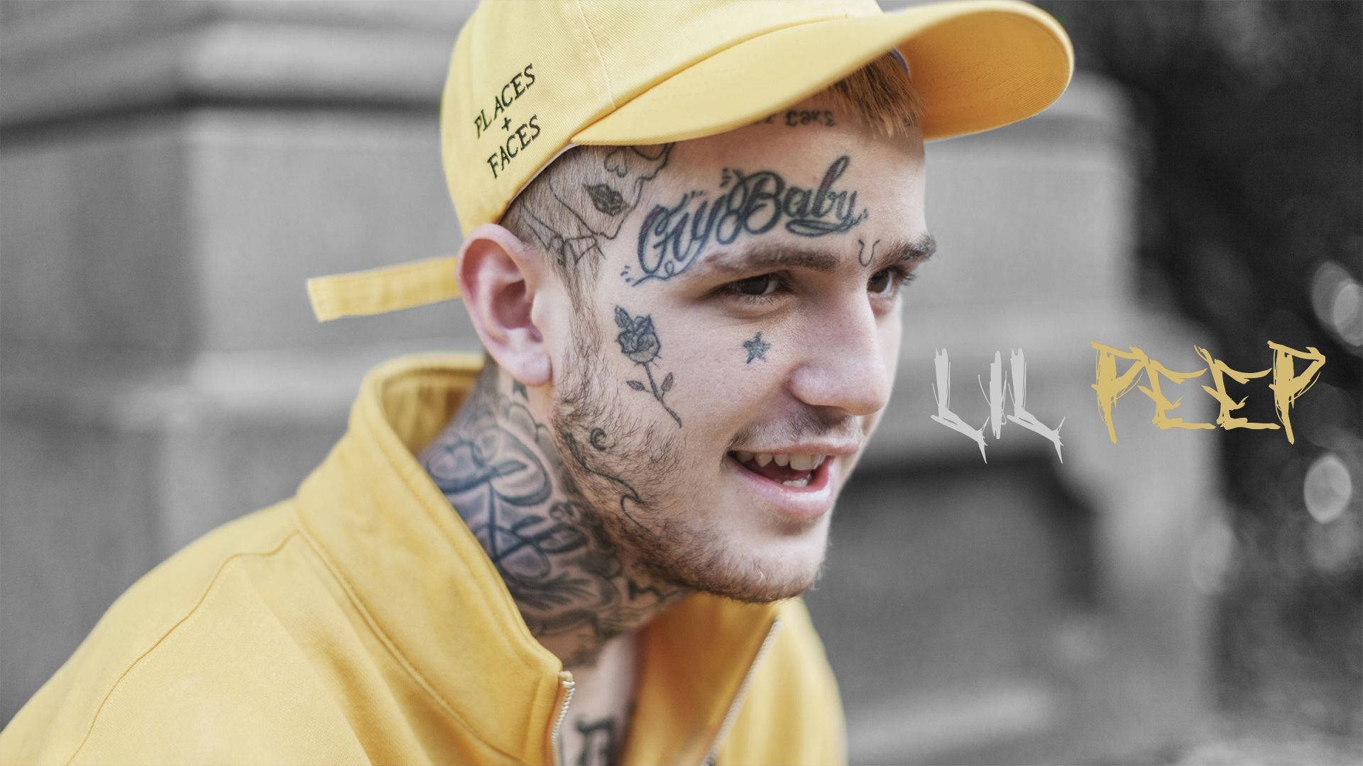 Peep 桌布 壁紙 — 一位有刺青、戴黃色帽子的年輕男子，穿著相配的黃色連帽衫，在模糊的城市背景下微笑。