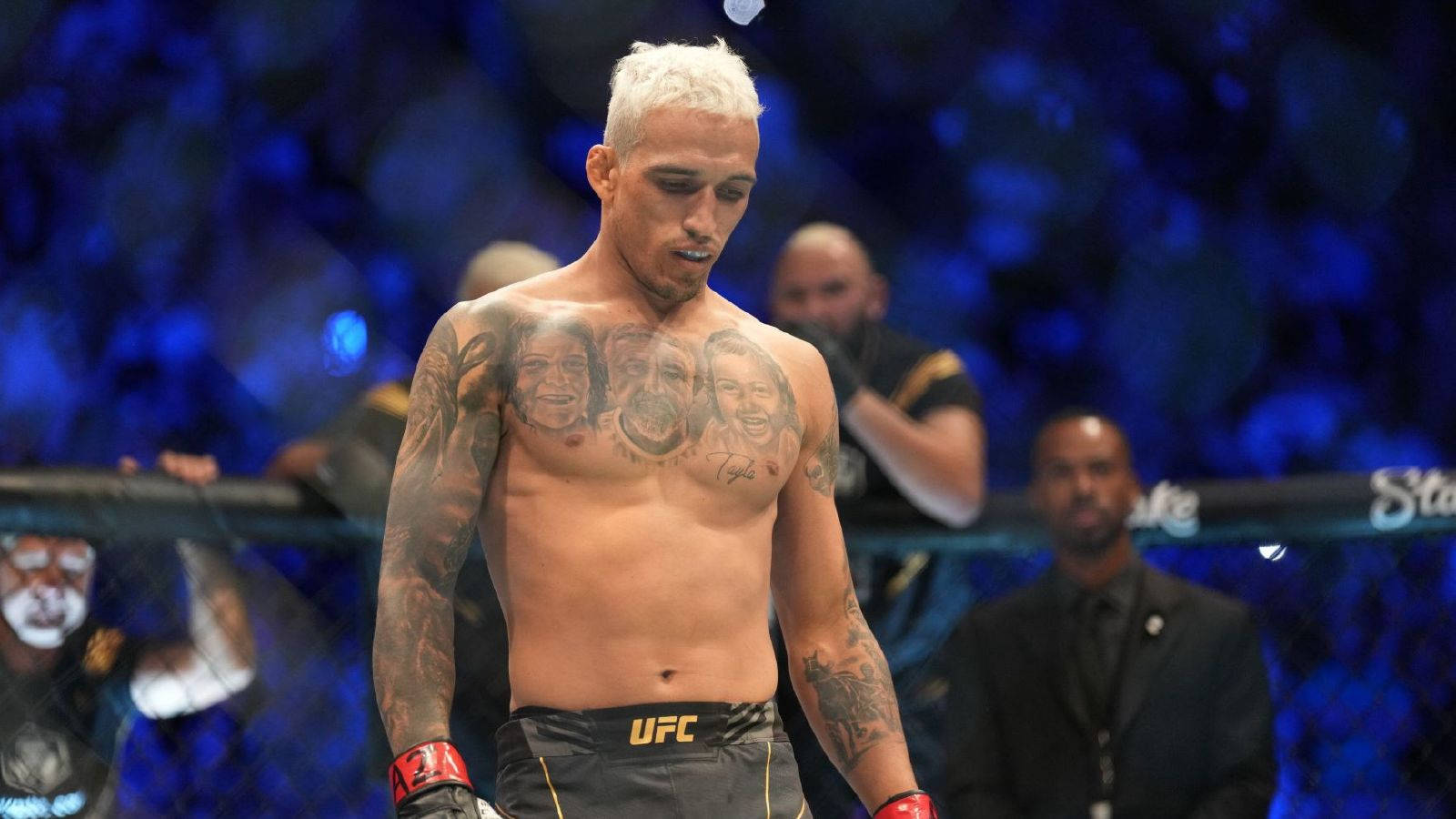MMA 桌布 壁紙 — 一位有刺青、染了鉑金色頭髮的UFC拳手在藍色場館燈光下沮喪地走在八角籠中。