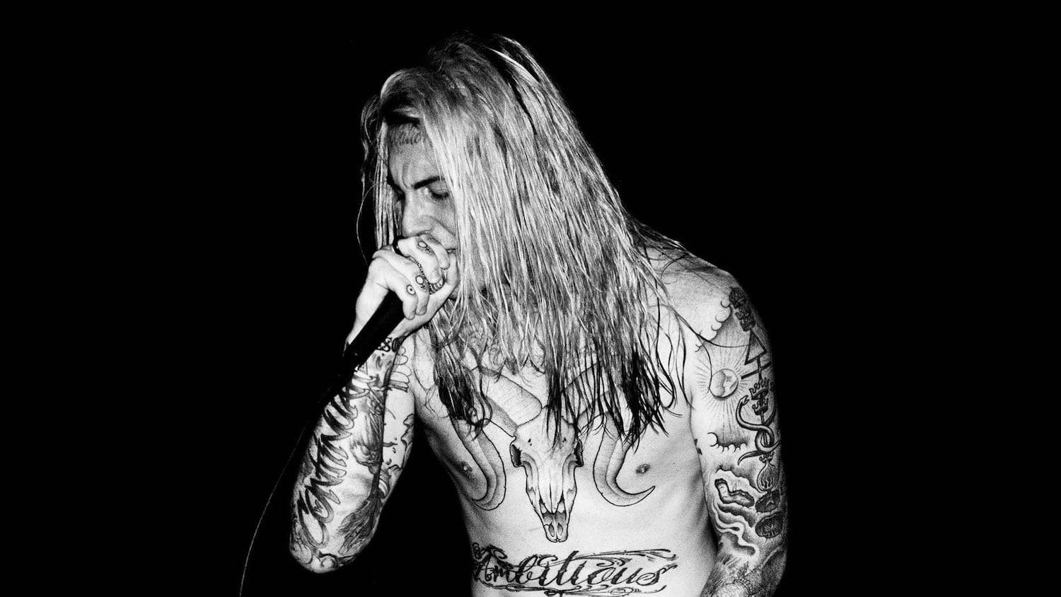 Ghostemane 桌布 壁紙 — 一位有刺青、長髮的音樂家，在純黑背景前，以高對比黑白風格對著麥克風唱歌。