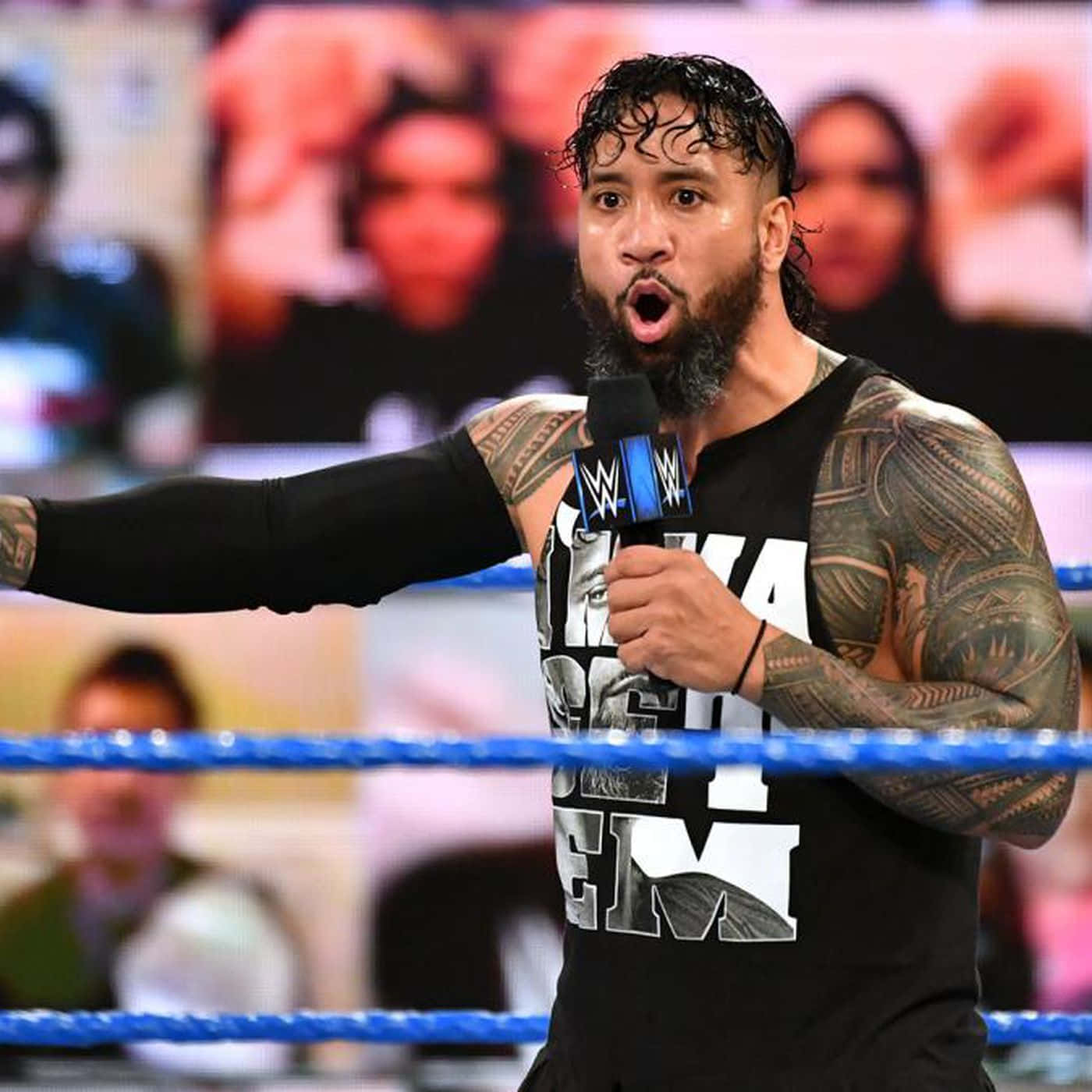 WWE 桌布 壁紙 — 一位有刺青和鬍鬚的摔角手在藍色環的摔角場內對著WWE麥克風大喊。