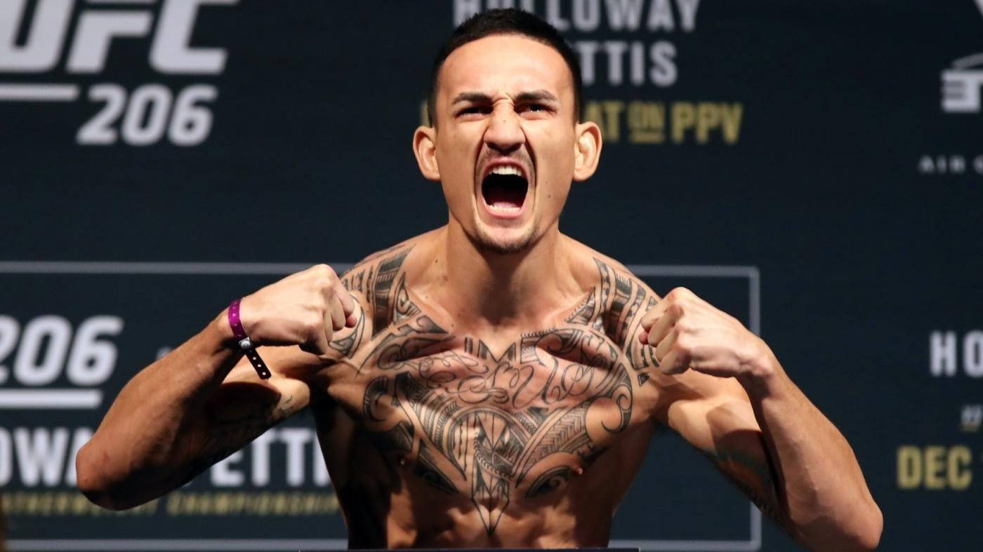 MMA 桌布 壁紙 — 一位有刺青的UFC拳手在明亮的場館燈光下，於稱重活動中舉起拳頭咆哮。