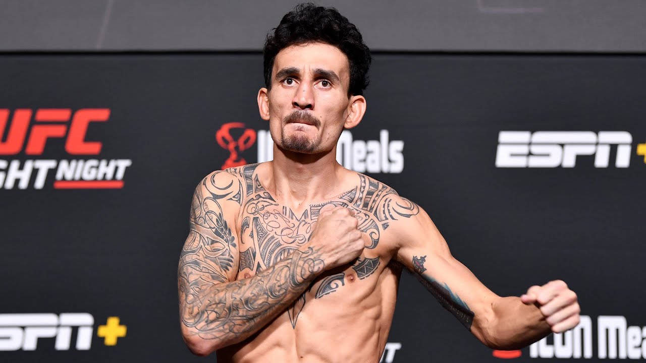 UFC 桌布 壁紙 — 一位有刺青的UFC拳手在稱重活動中展示肌肉，背後有ESPN和UFC品牌標誌。