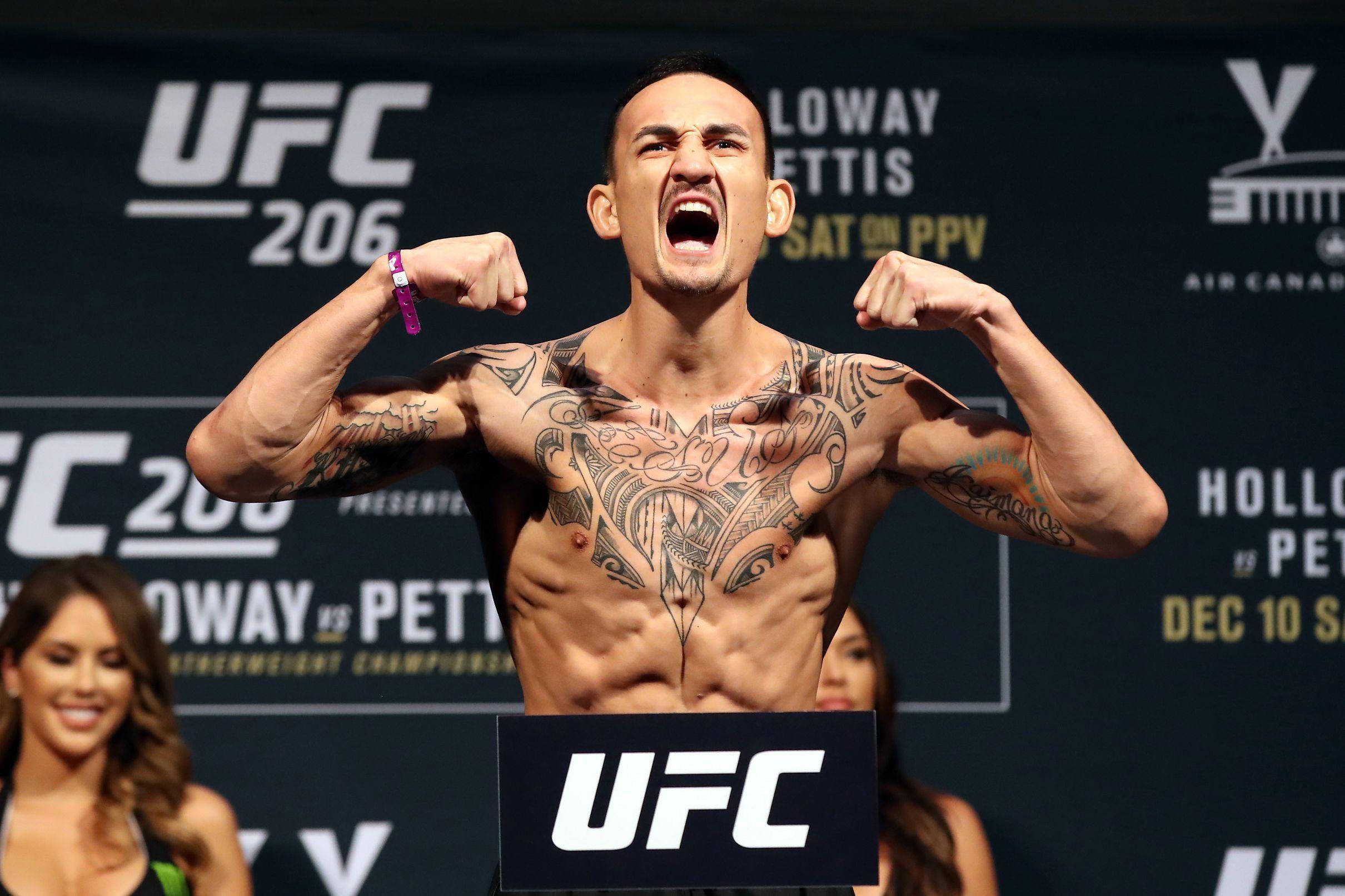 MMA 桌布 壁紙 — 一位有刺青的UFC拳手在稱重活動中展示肌肉並勝利咆哮，背後有宣傳橫幅。