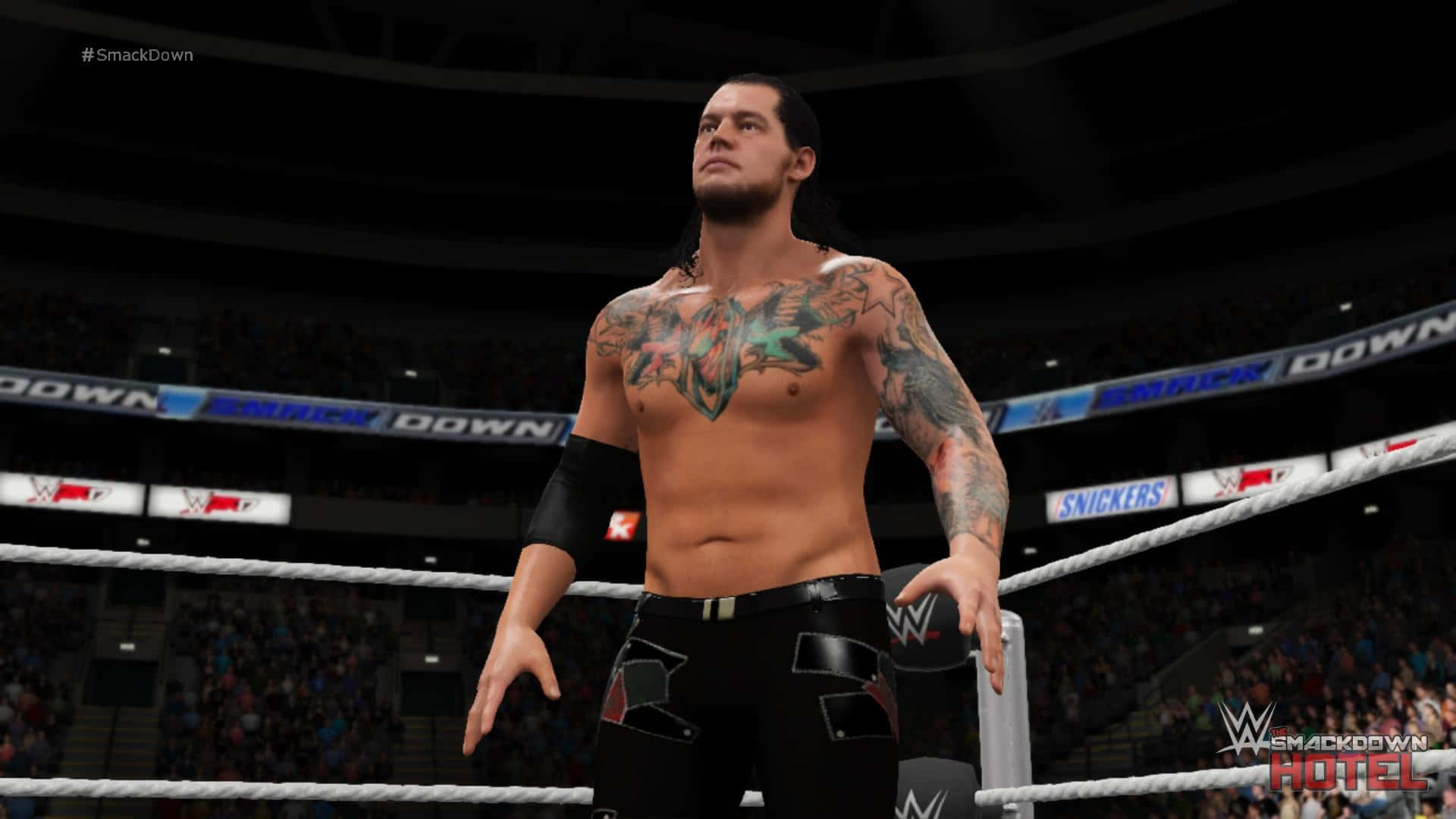 Tattoo 桌布 壁紙 — 一位有刺青的摔角手在場館燈光下自信地站在摔角擂台上，周圍擠滿了觀看的觀眾。